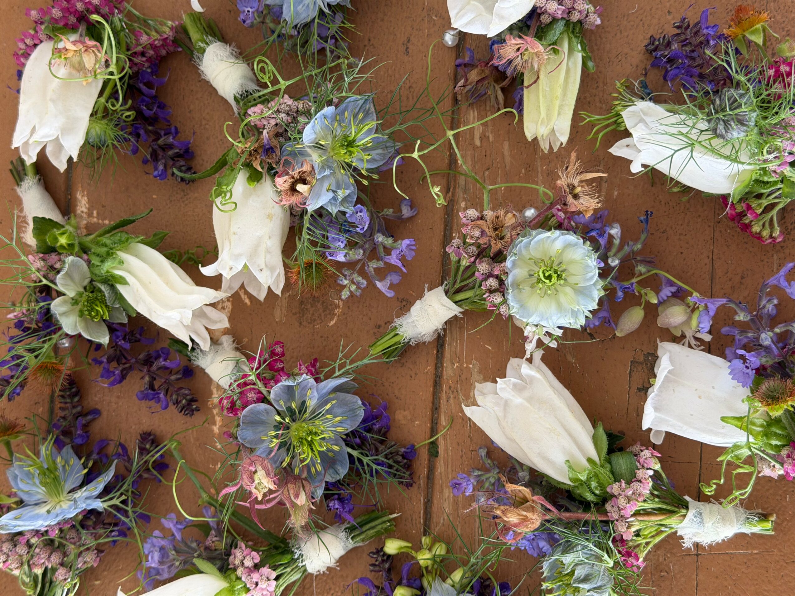 Various flowers and ribbons arranged on a surface, with some flowers wrapped in white ribbons.
