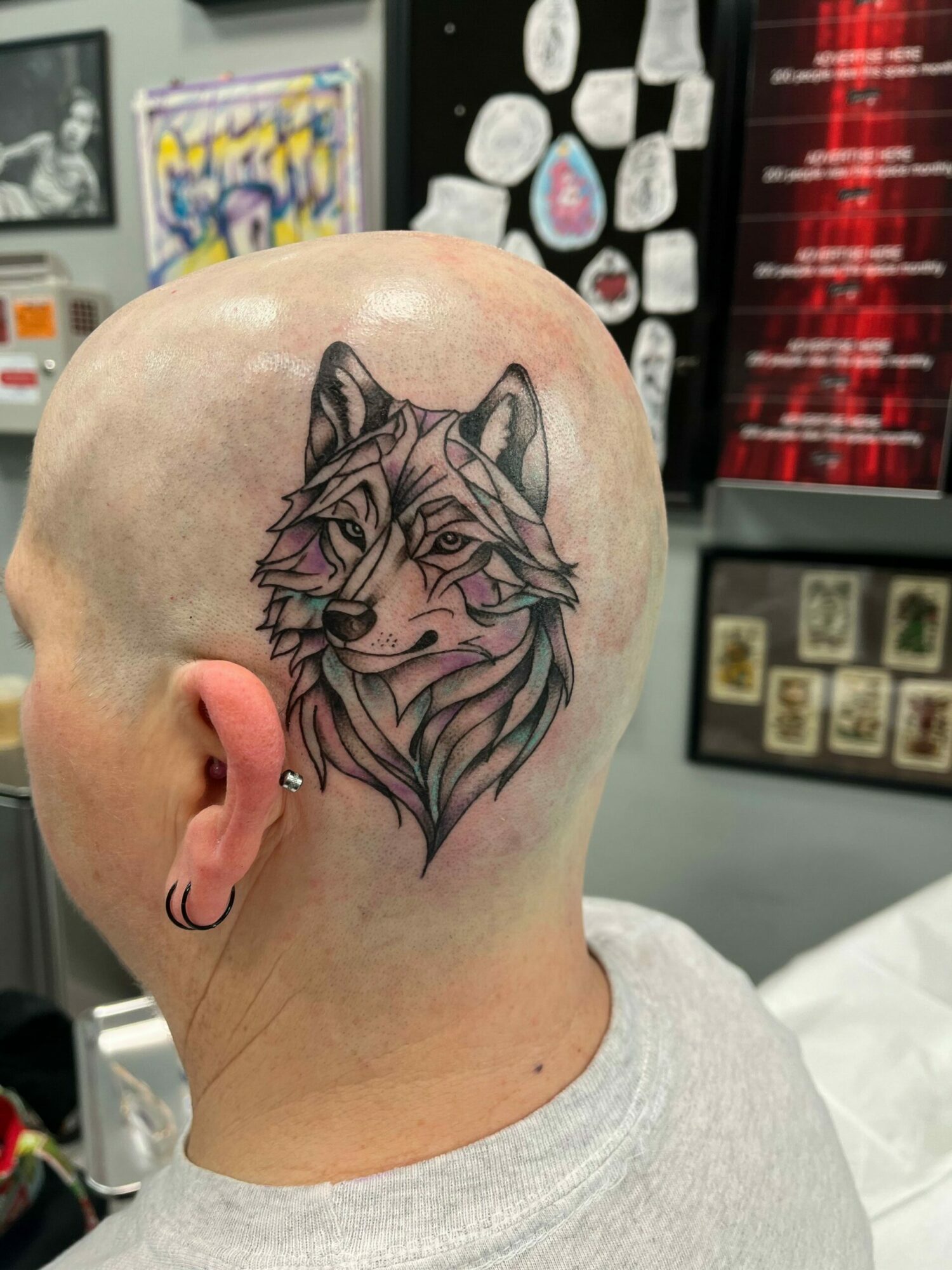 Tattoo of a lion's face on a person's head, with detailed mane and facial features, in black and pink ink.