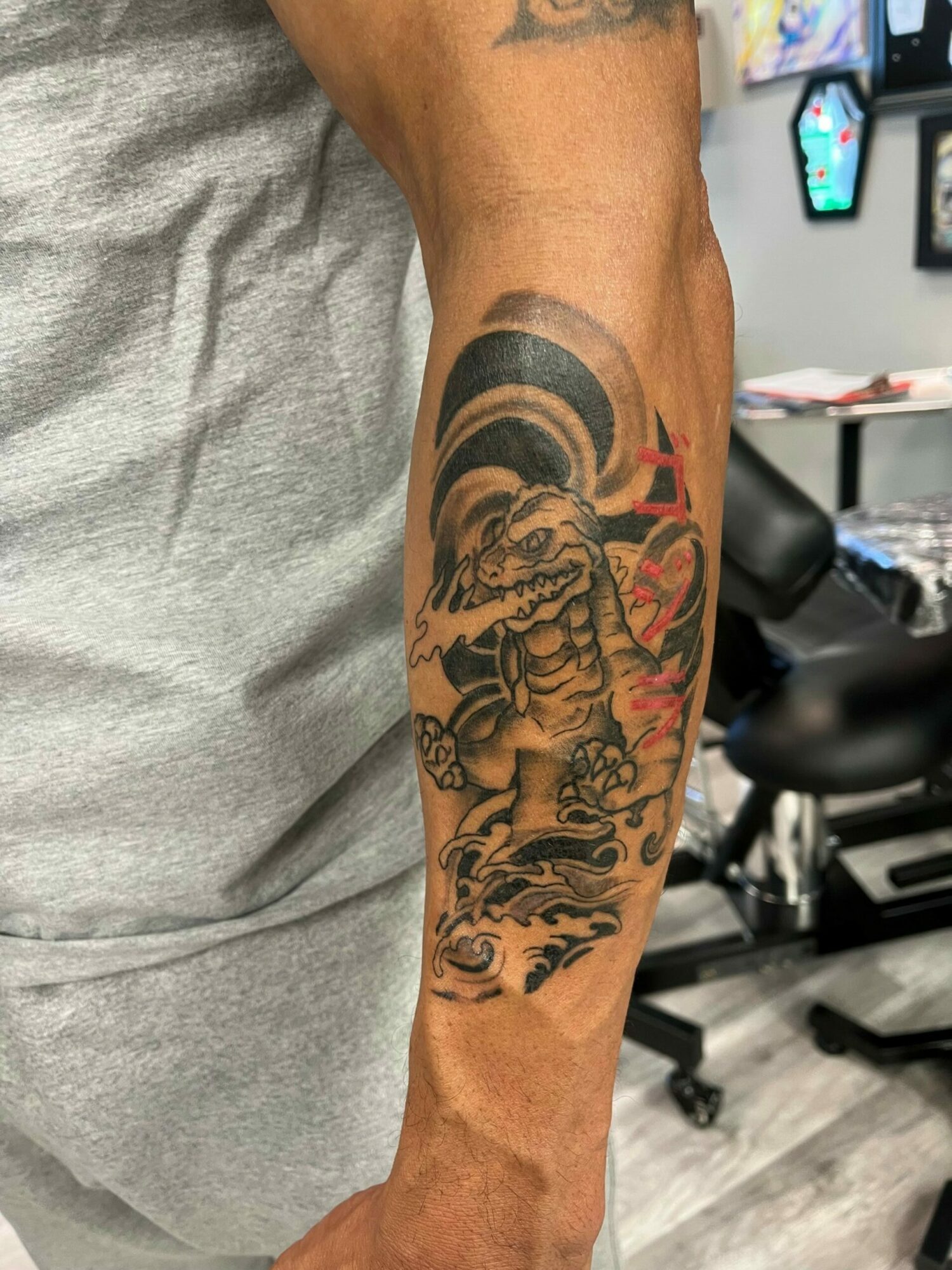 Tattoo of a fierce tiger with detailed stripes and facial features on a person's arm, with a background of black and red elements.