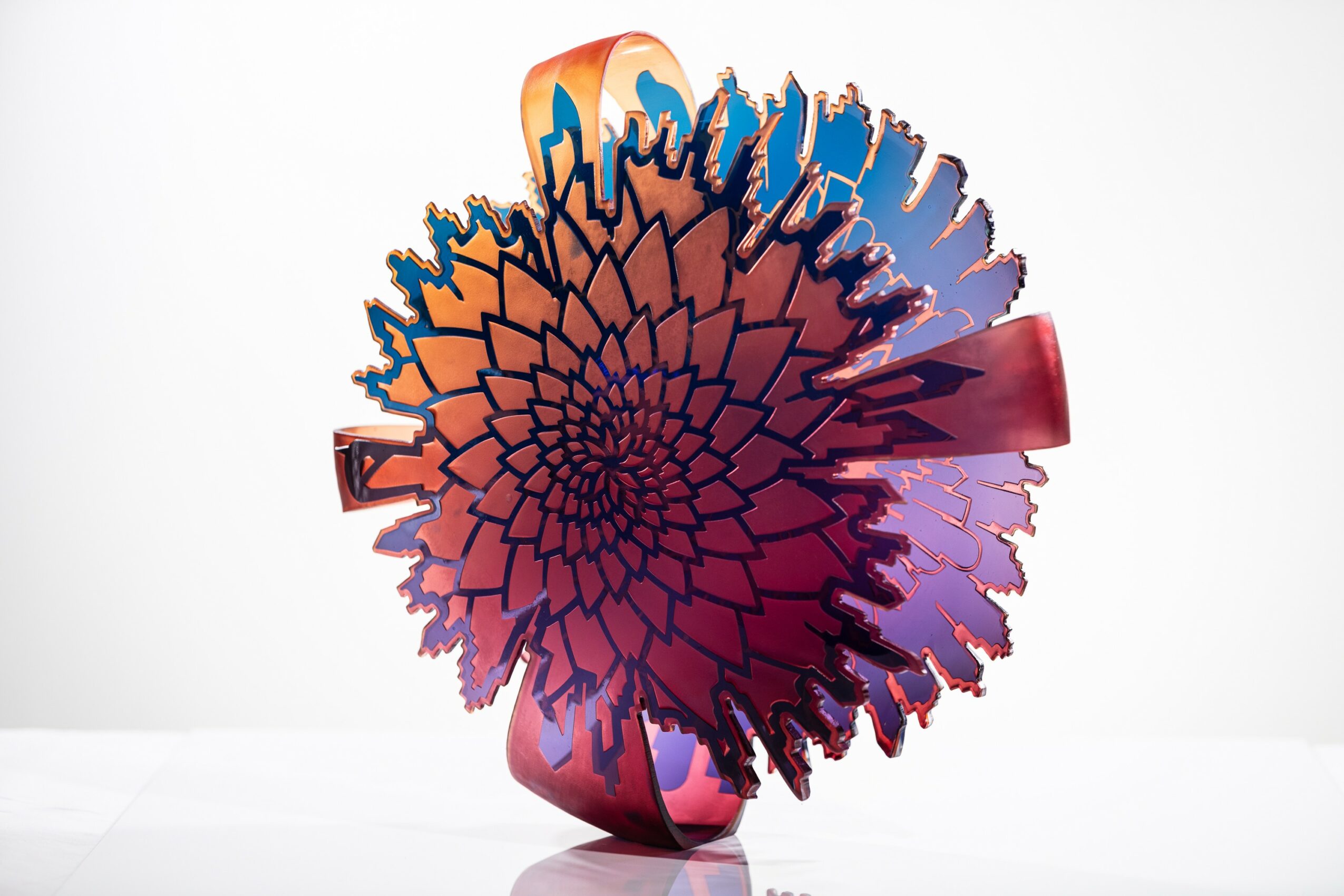 Colorful glass sculpture with a spiral pattern, set against a white background.