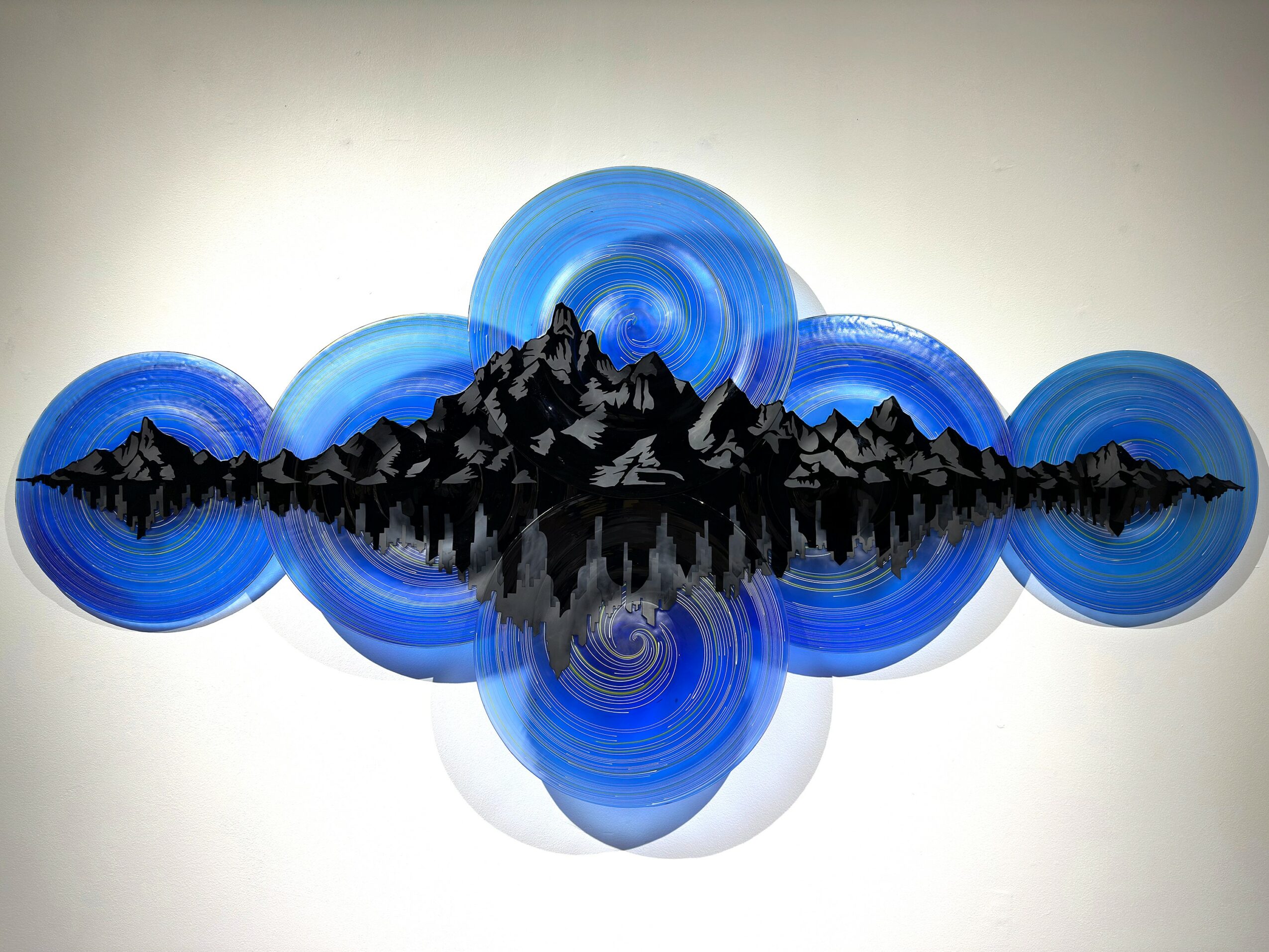 Abstract artwork with blue circular shapes and a black mountain silhouette in the center.