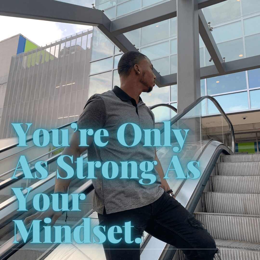 A man standing on an escalator in a modern building with glass walls, looking to the side, with motivational text overlay.