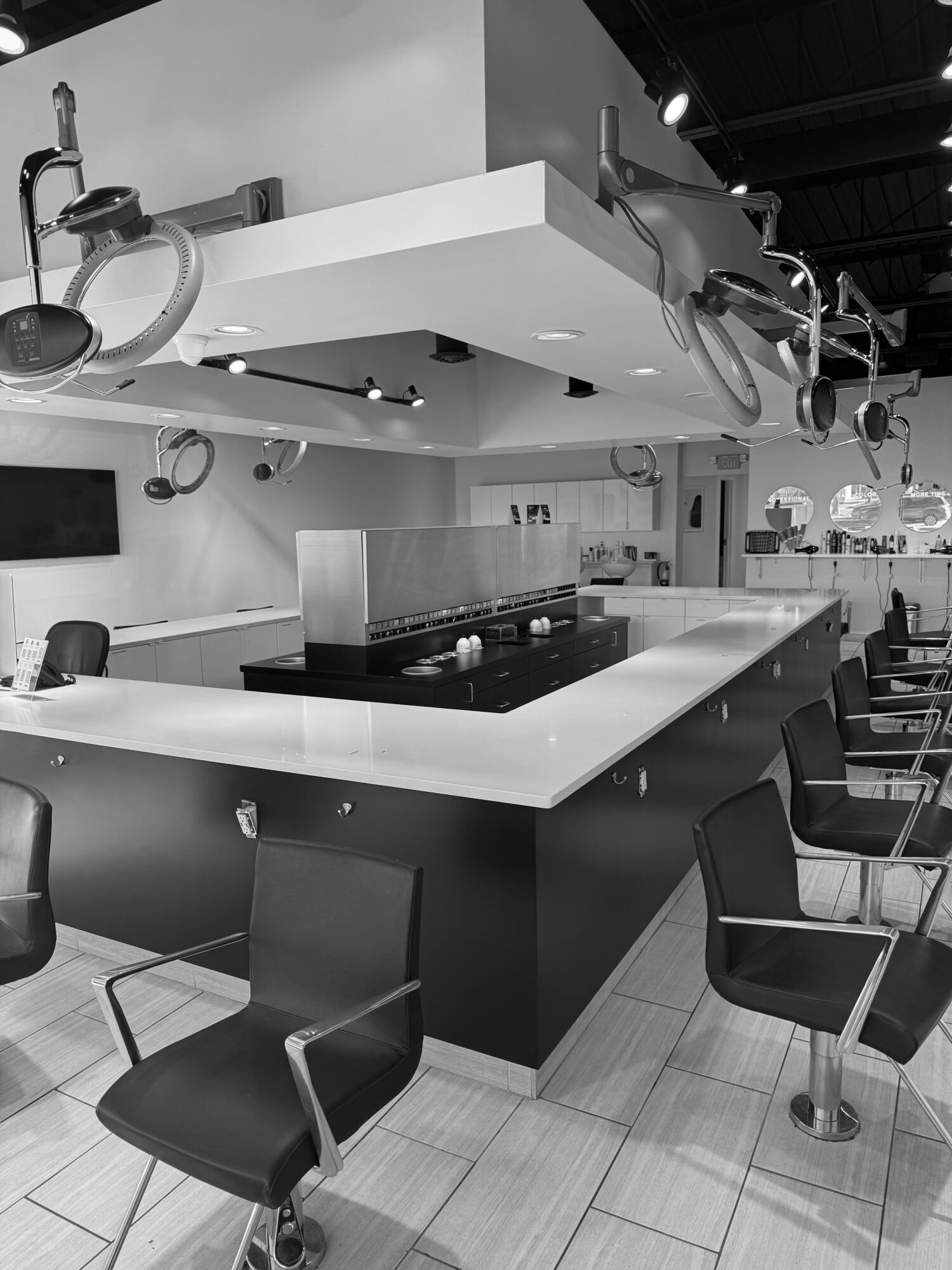 Modern bar counter with chairs, overhead lights, and a clean, minimalist design in a well-lit space.