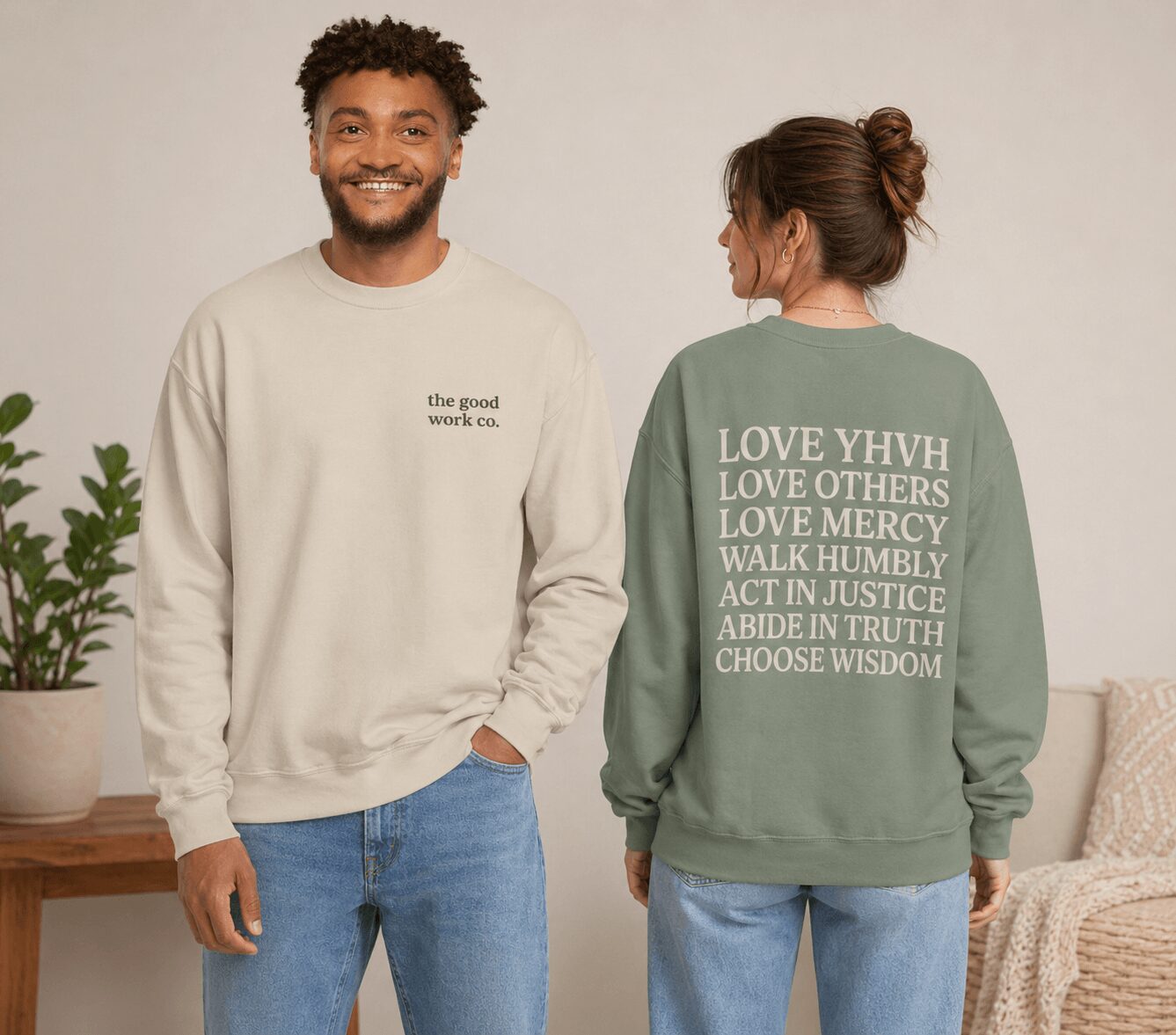 A smiling man faces forward, wearing a cream sweatshirt, and a woman with her back turned, wearing a green sweatshirt with text.