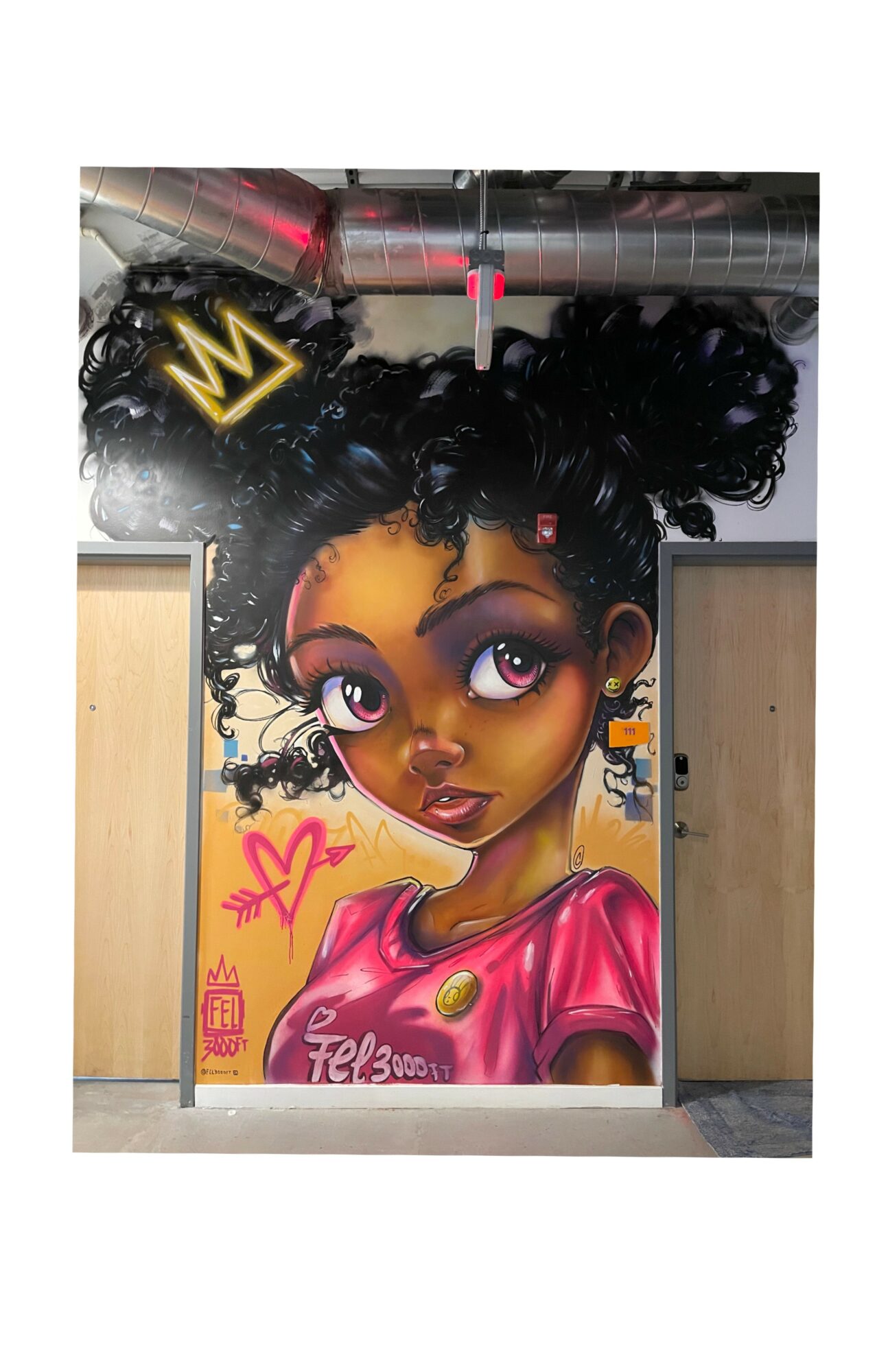 Colorful mural of a young girl with large eyes, curly hair, and a pink shirt, with a crown above her head.