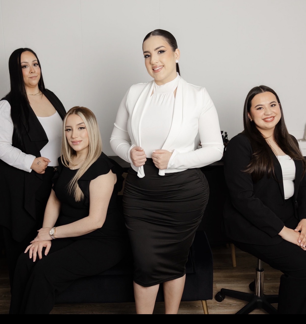 Group of five women in professional attire posing against a plain background.