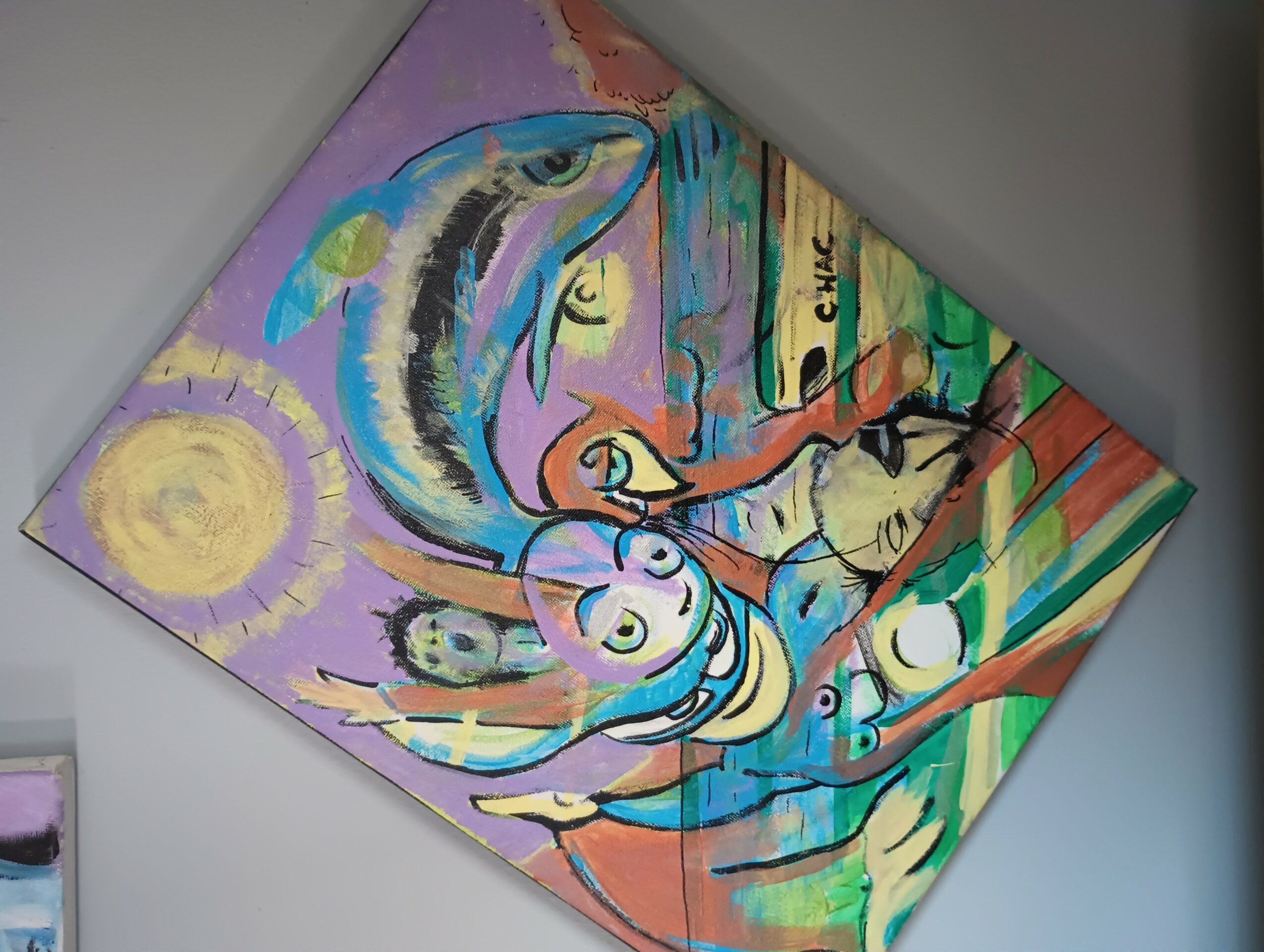 Abstract colorful painting with a fish, face, and various shapes, tilted on a wall.