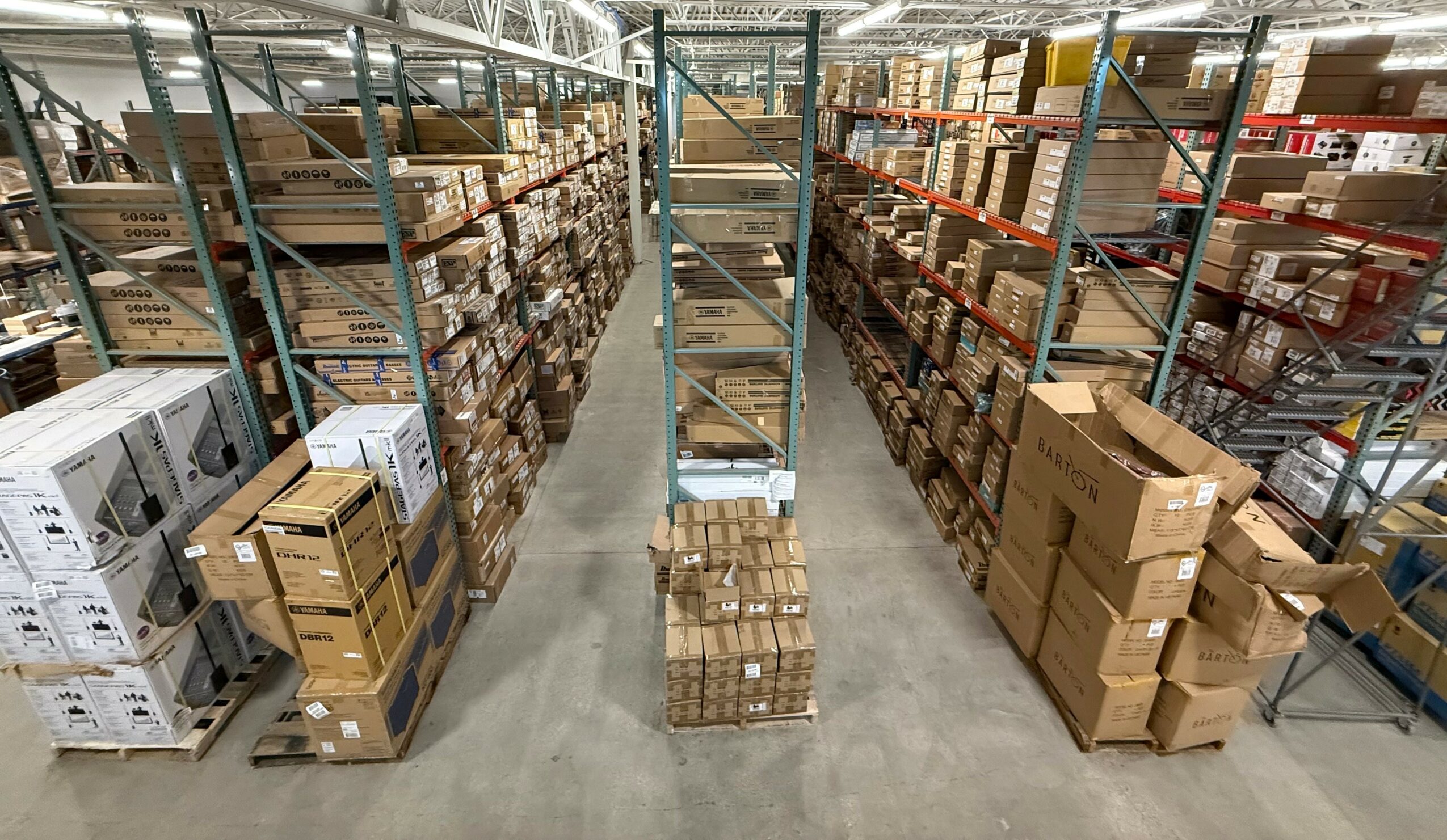 Warehouse aisle with shelves filled with boxes and packages, viewed from above.