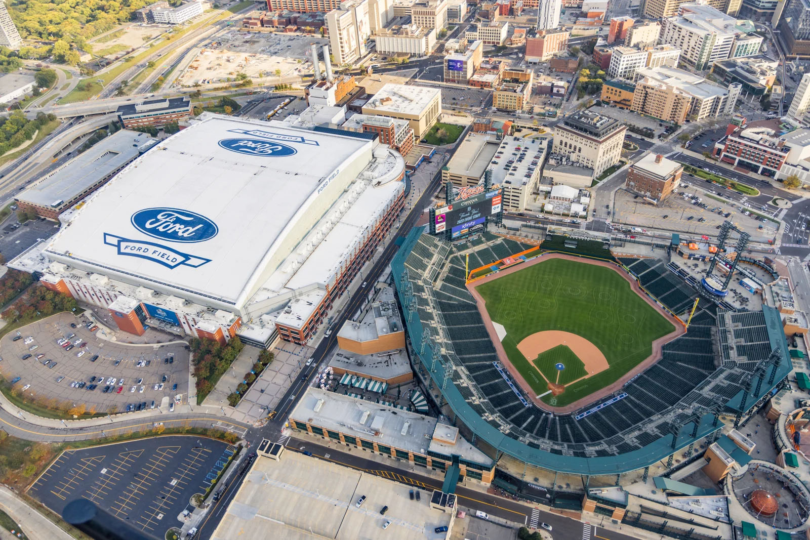 Aerial view of a sports stadium with a baseball field and a large arena with Ford branding nearby.