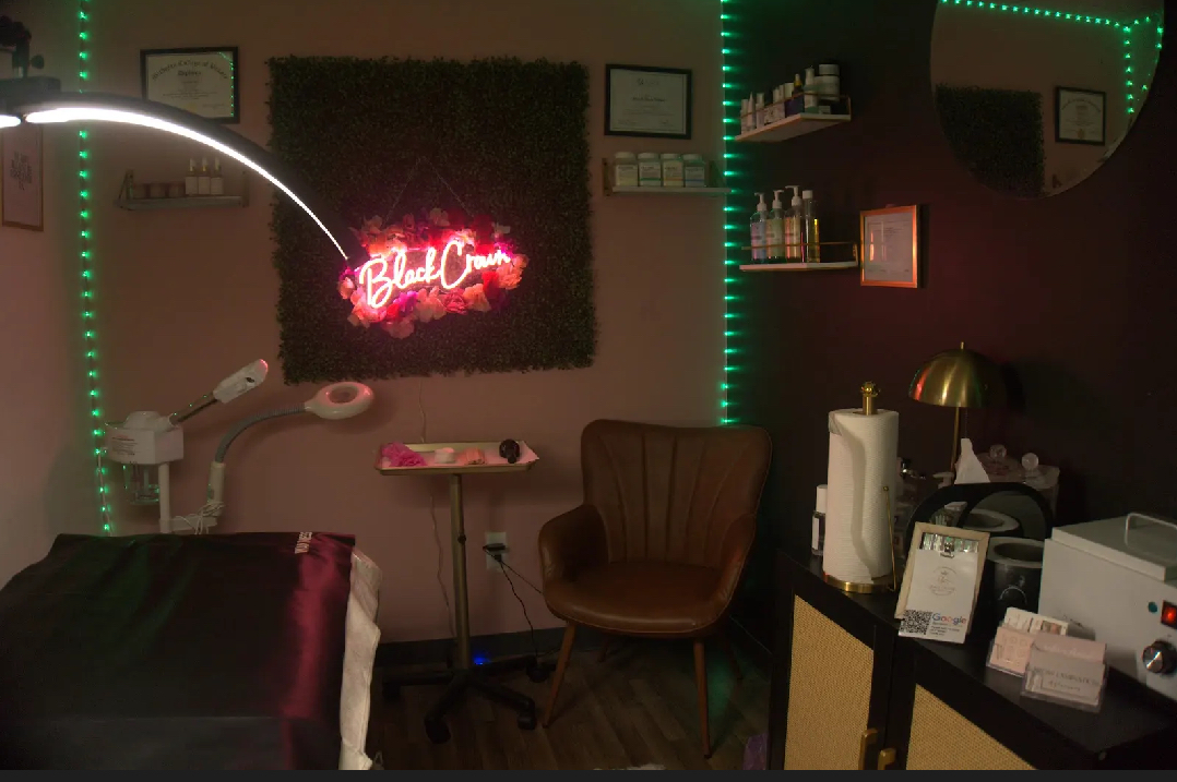 Room with a neon sign, a brown chair, shelves, and a desk with office supplies, illuminated by green LED lights.