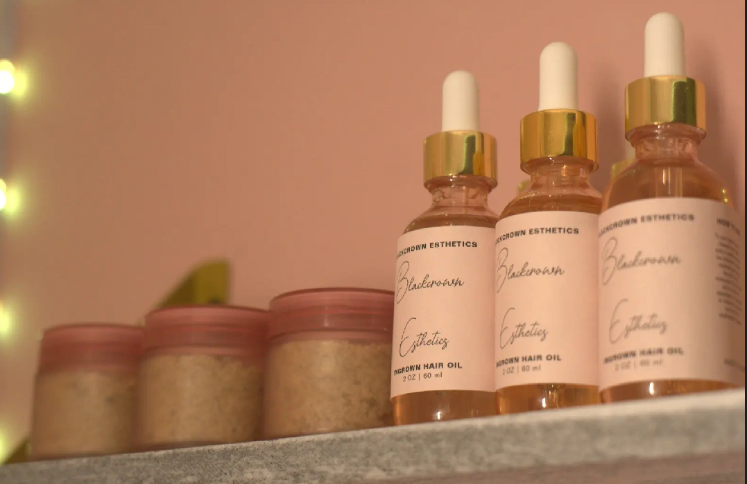 Three bottles with dropper caps and three jars with pink lids on a shelf, against a pink wall.