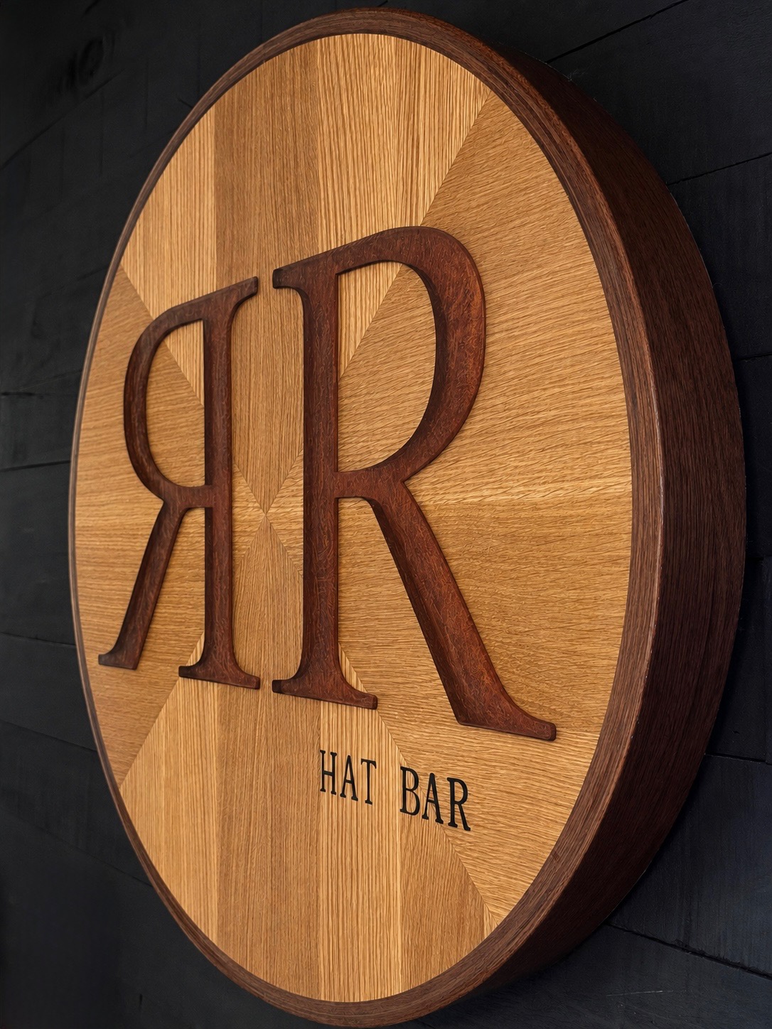 Round wooden sign with large initials and text reading 'HAT BAR'.