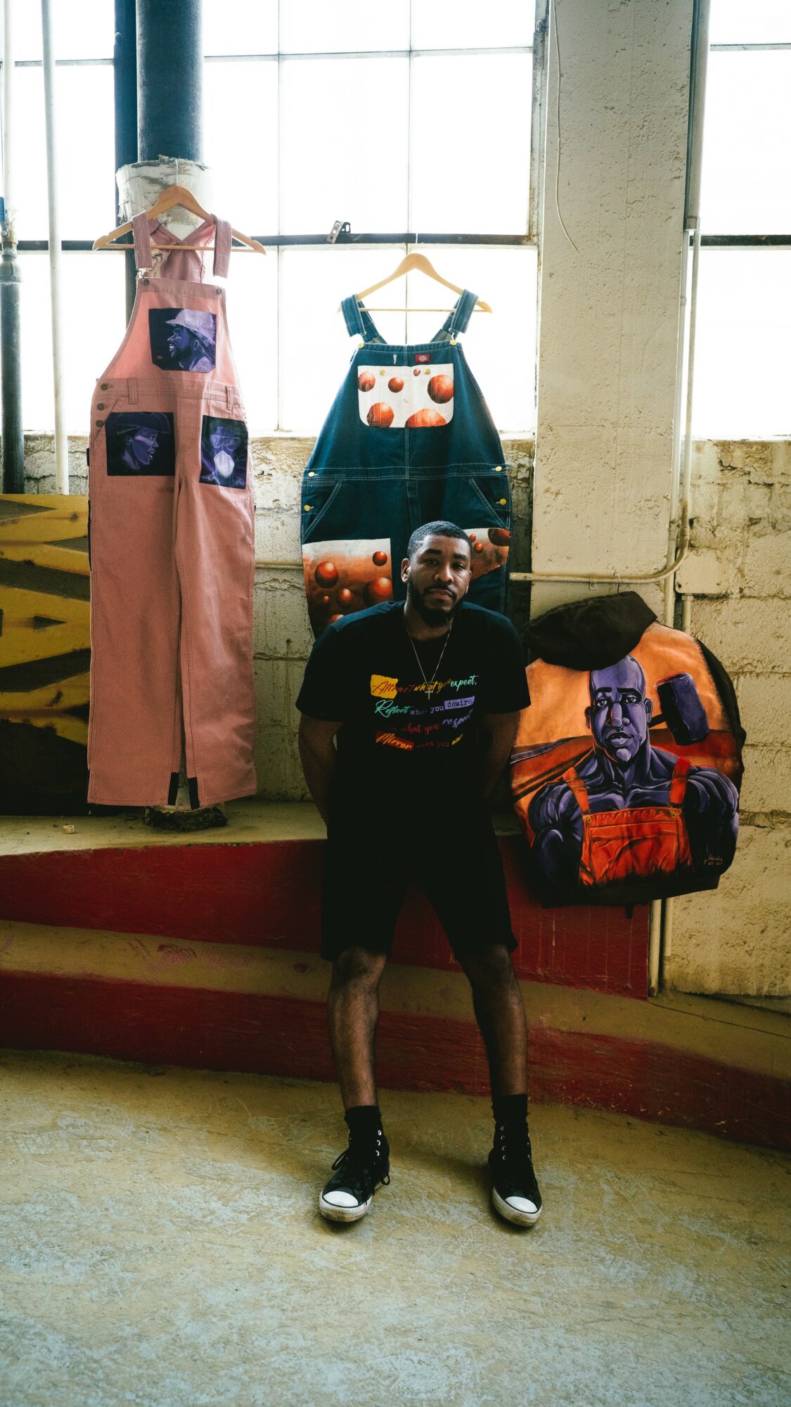 Person standing in front of display of clothing and bags, with large windows in the background.