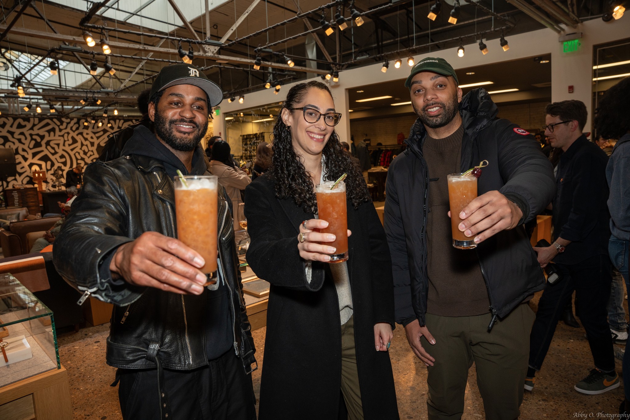 Three people holding drinks and smiling in a bar or restaurant setting.
