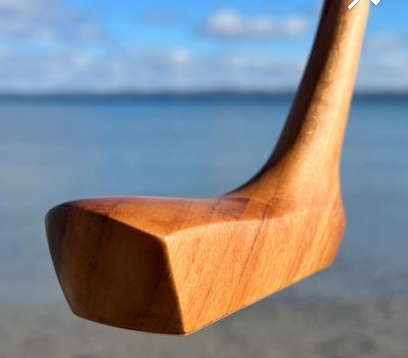 Close-up of a wooden object with a curved handle against a beach background.