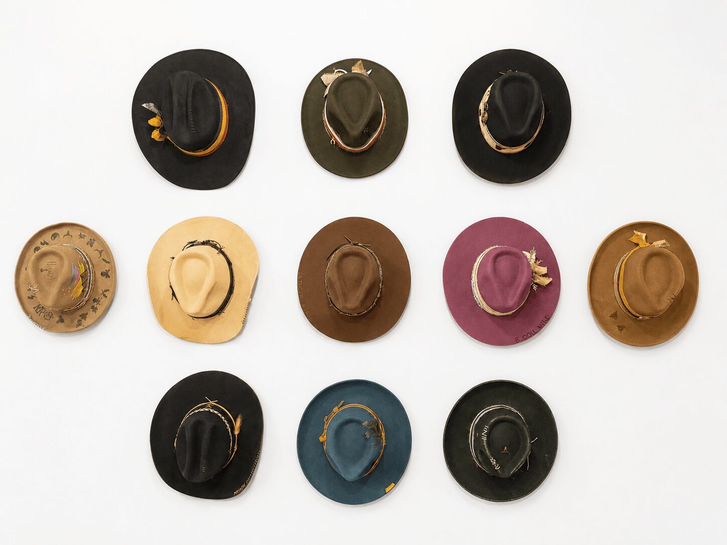 Collection of twelve hats arranged in three rows, various colors and styles, on a white background.