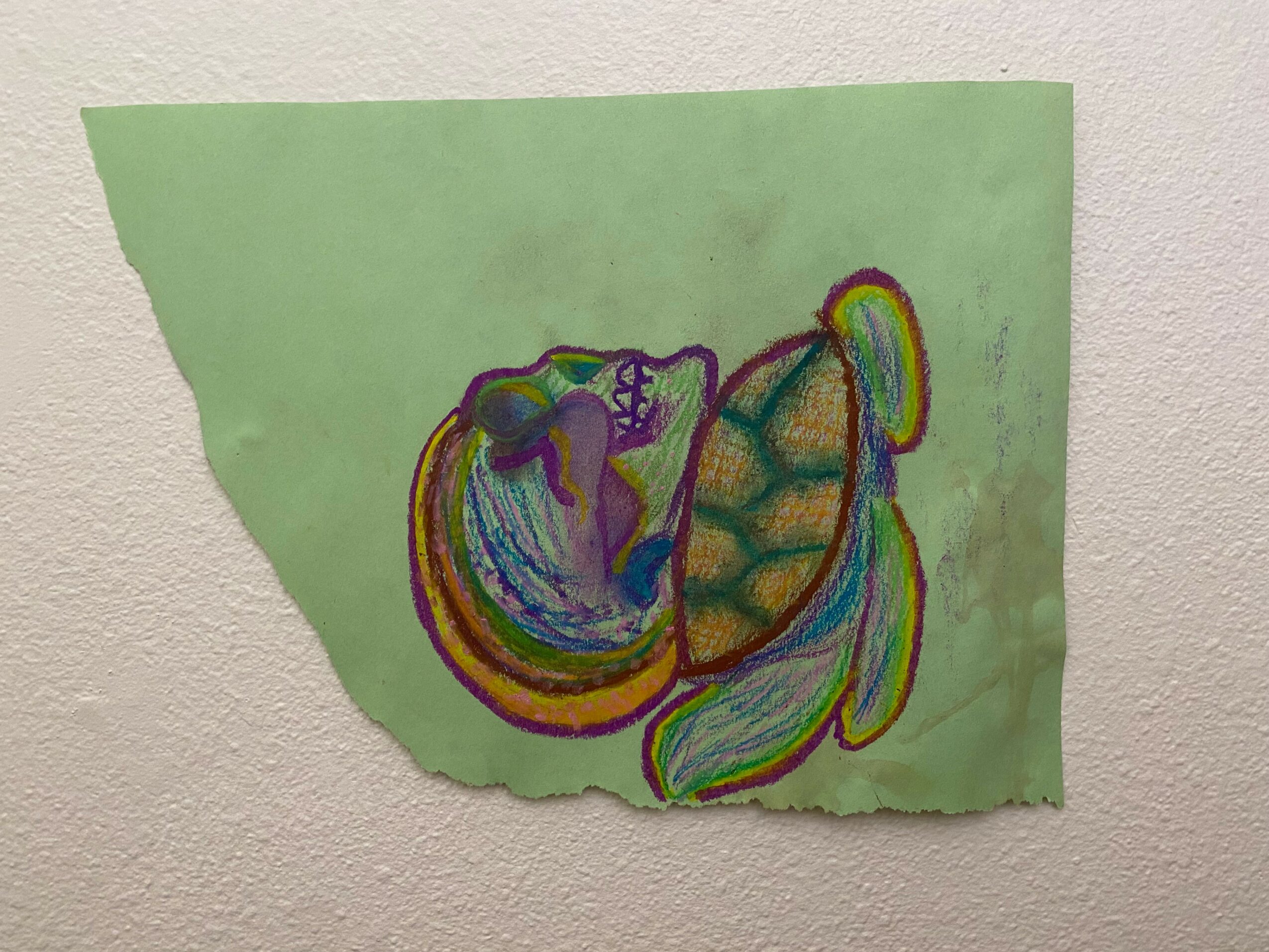 Colorful drawing of a horse on green paper, attached to a wall, with a torn left edge.