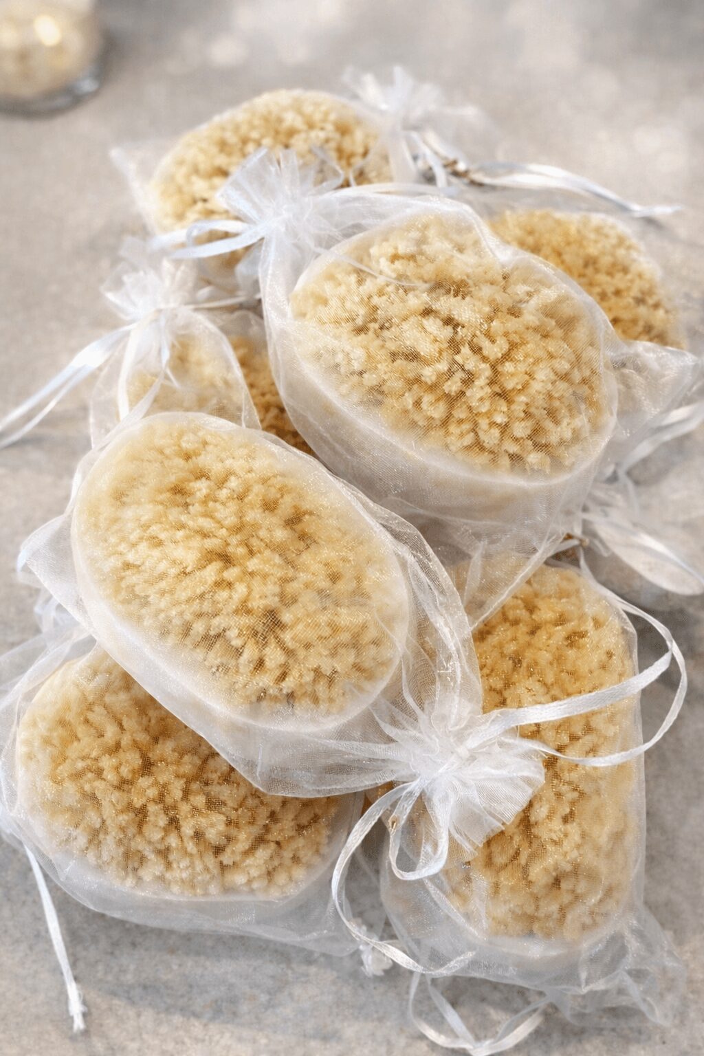 Several packaged baked goods with crumbly topping, wrapped in clear plastic and tied with white ribbons, on a gray surface.