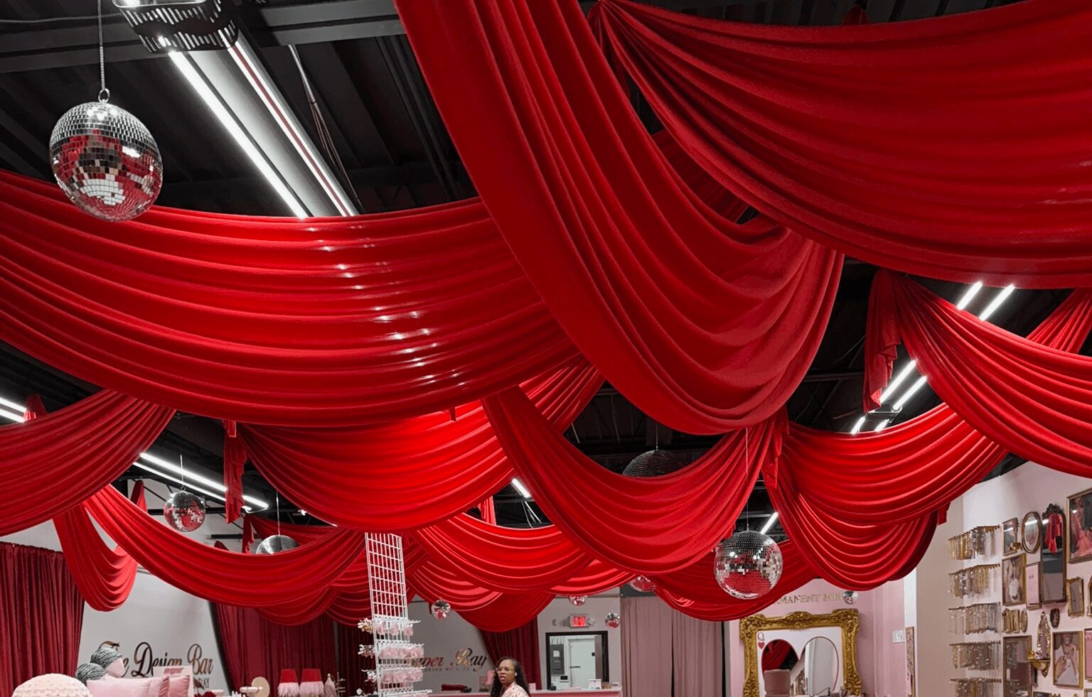 Red draped fabric ceiling with disco balls and store shelves visible below.