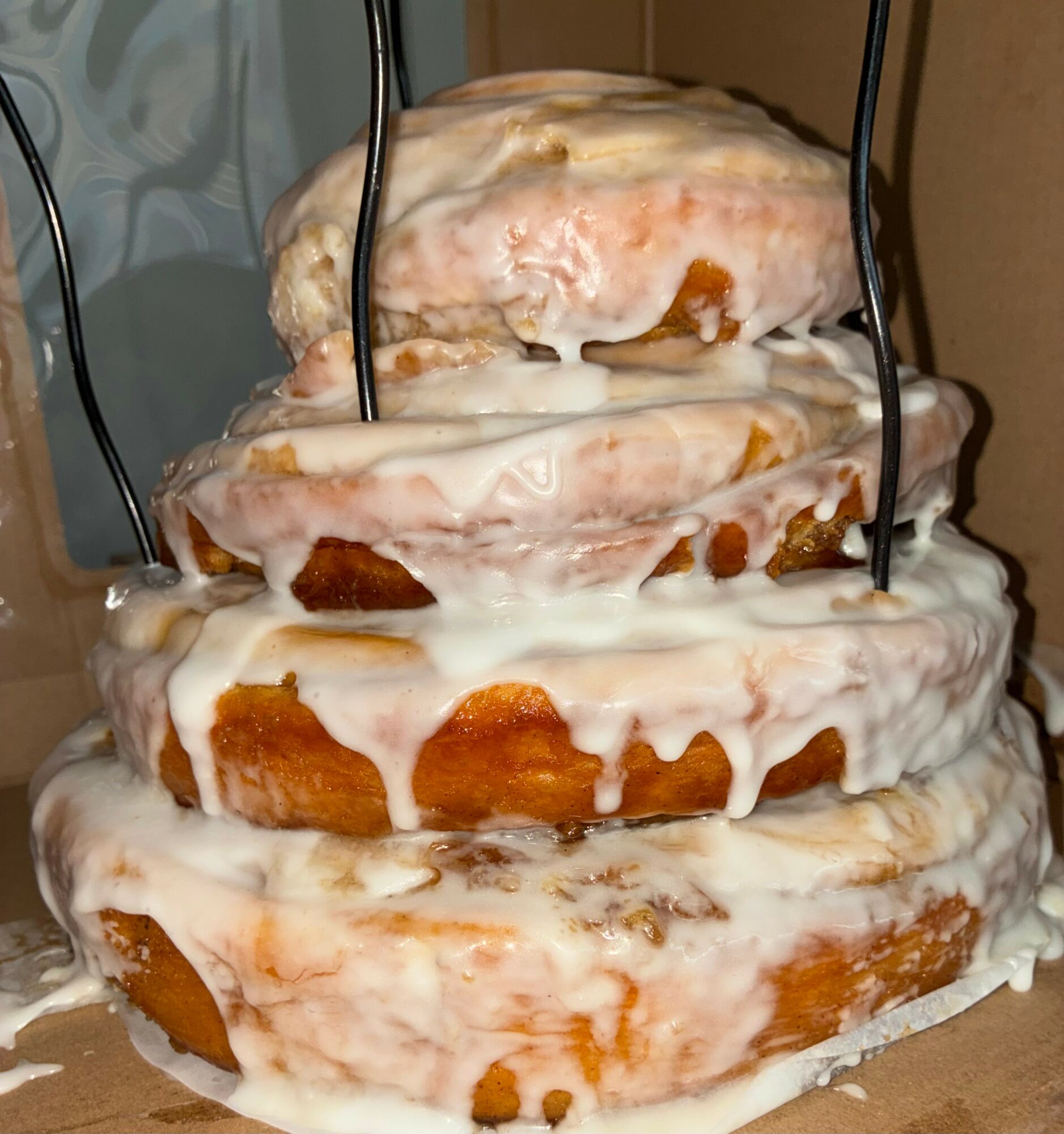 Four stacked donuts covered in white glaze with black wires around them, melting and dripping.