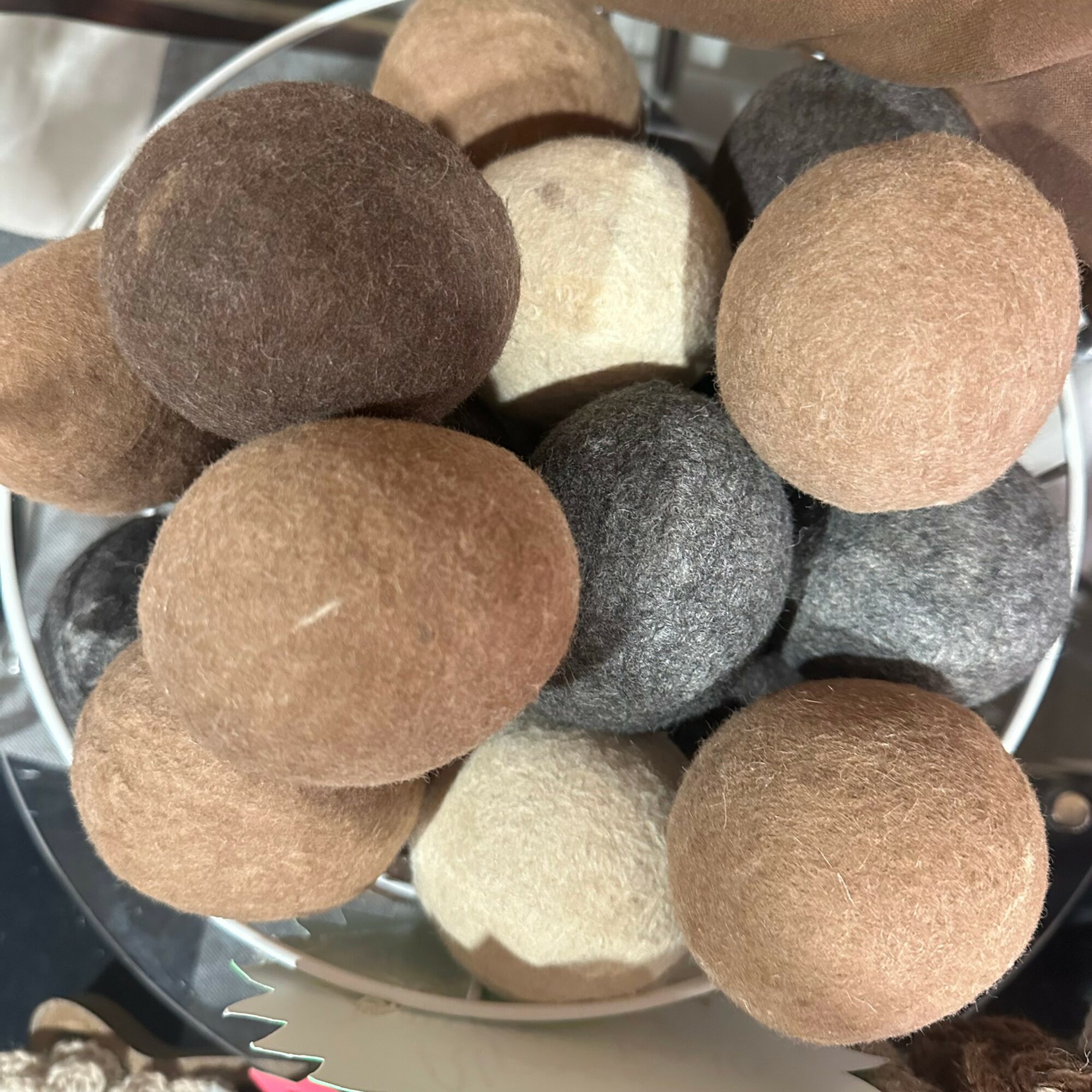 Collection of felted stones in various shades of brown, gray, and cream, arranged in a basket.
