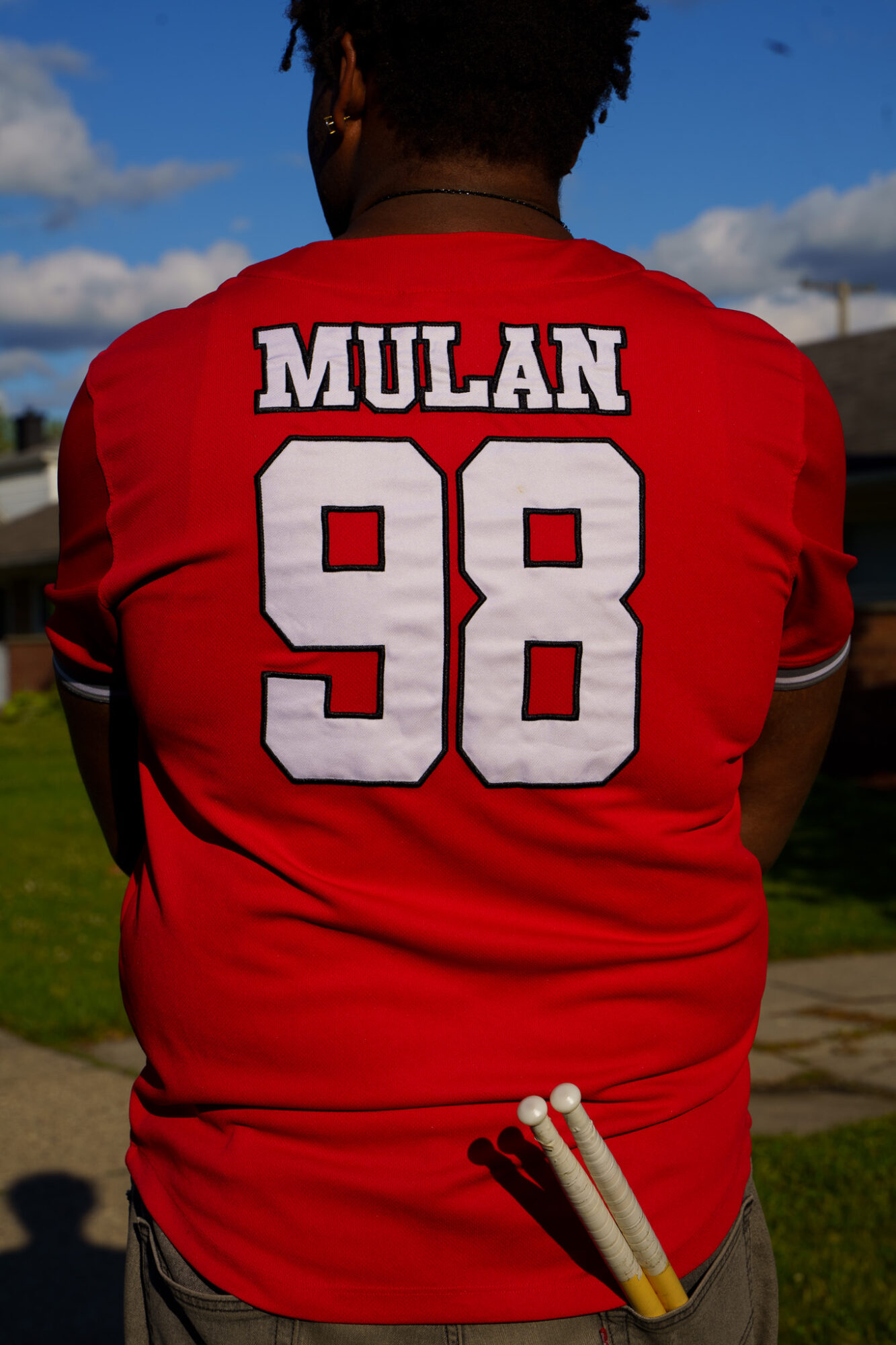 Person wearing a red sports jersey with 'MULAN' and the number 98 on the back, outdoors on a sunny day.
