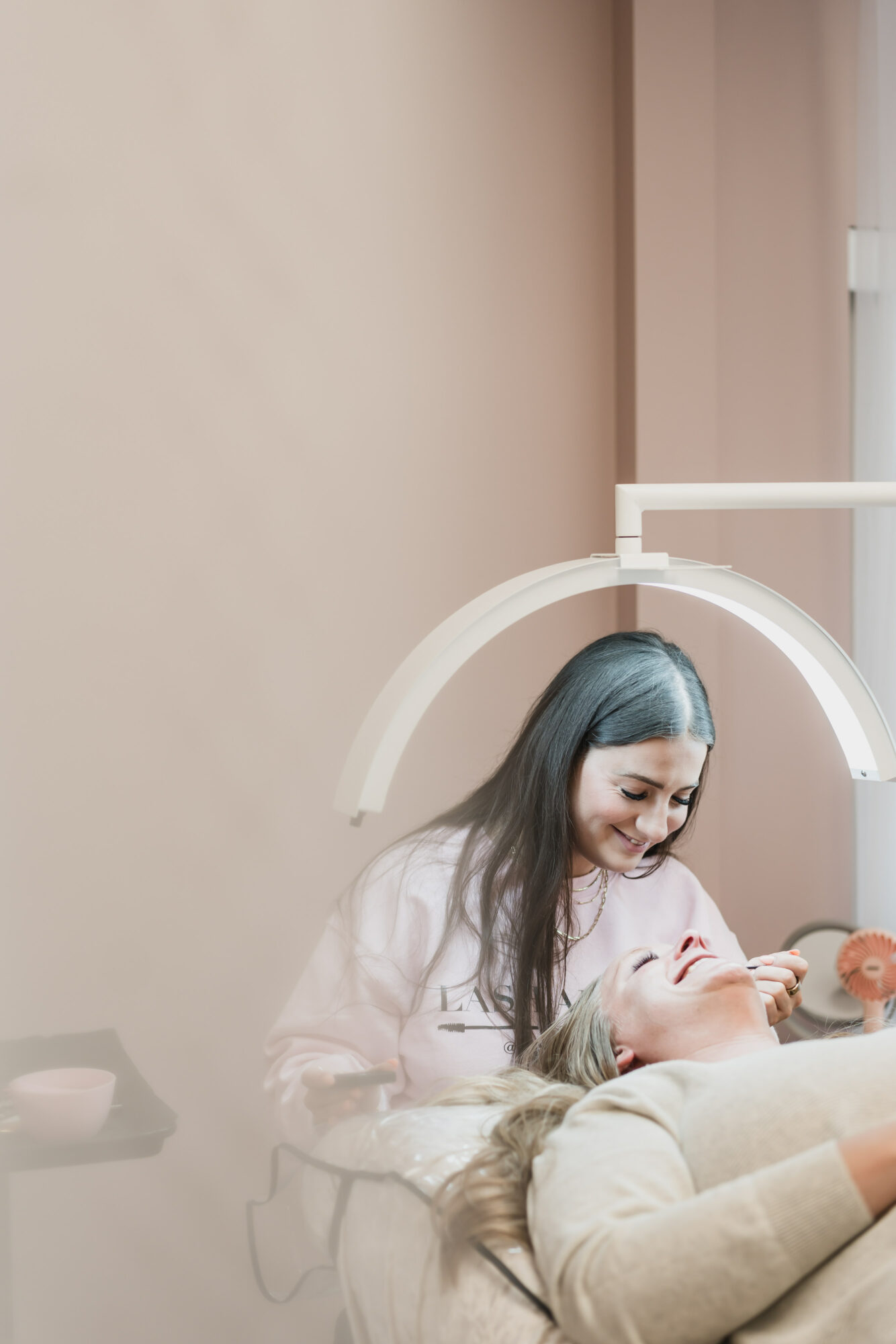 A woman with long dark hair leaning over a person lying in a medical bed, in a clinical setting.