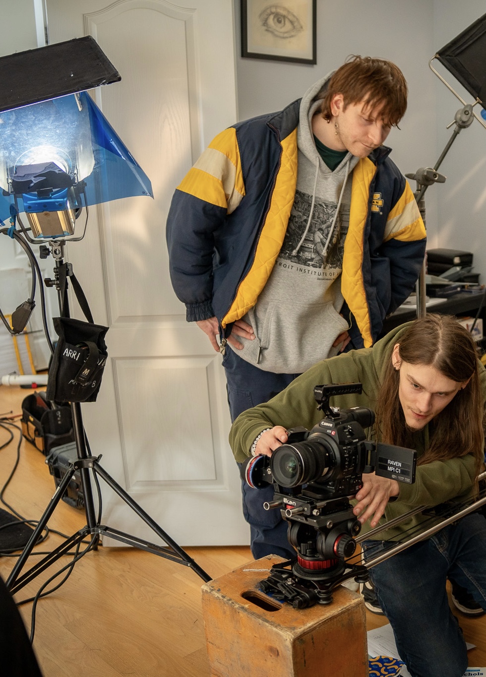 Two people working with a camera and lighting equipment in a studio, one adjusting the camera and the other observing.