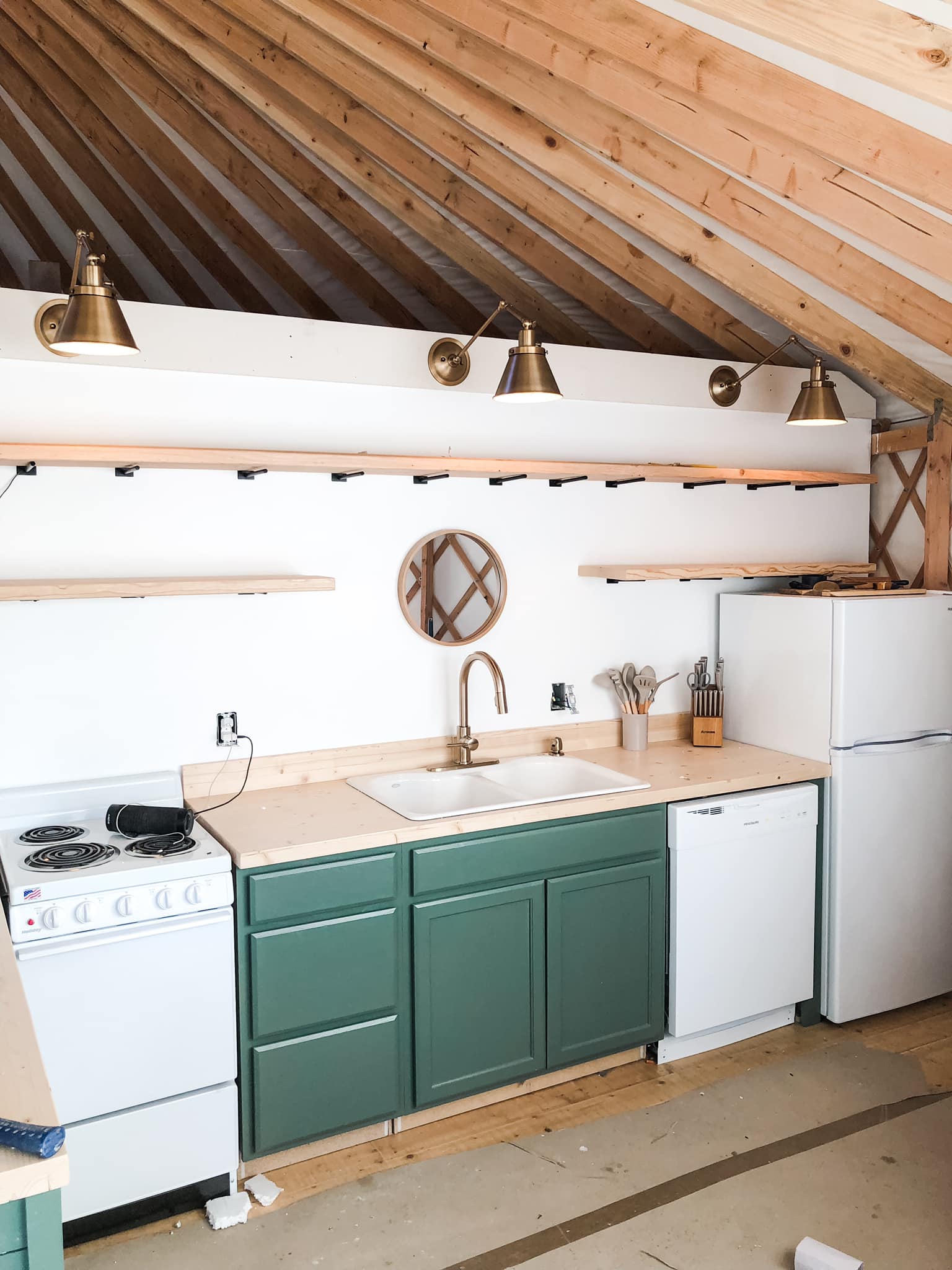 Kitchen with green cabinets, white appliances, wooden ceiling, and a small round mirror on the wall.