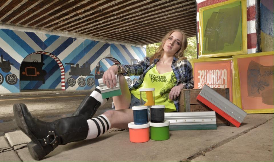 Person sitting on the floor with colorful boxes and stacked cans, leaning against a wall with a train mural.