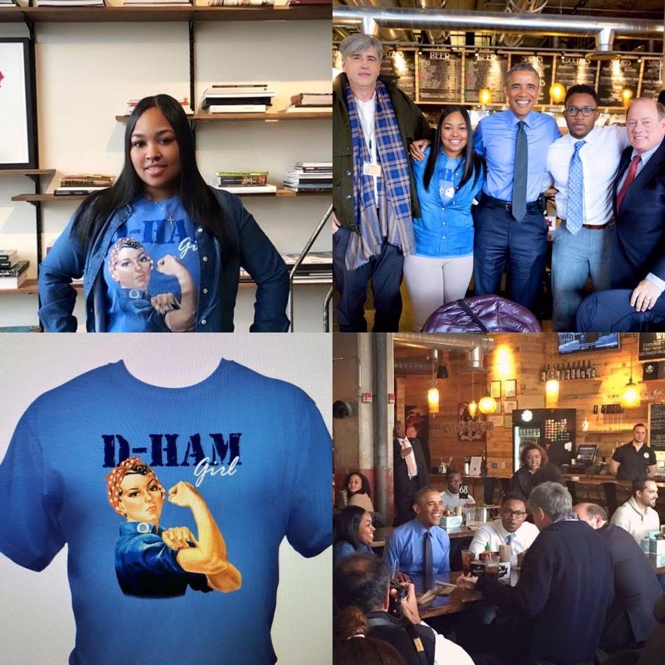 Group of people in a restaurant, some wearing blue, with a woman in the foreground wearing a blue jacket. A blue T-shirt with a graphic of a woman and the text 'D-HAM girl' is also visible.