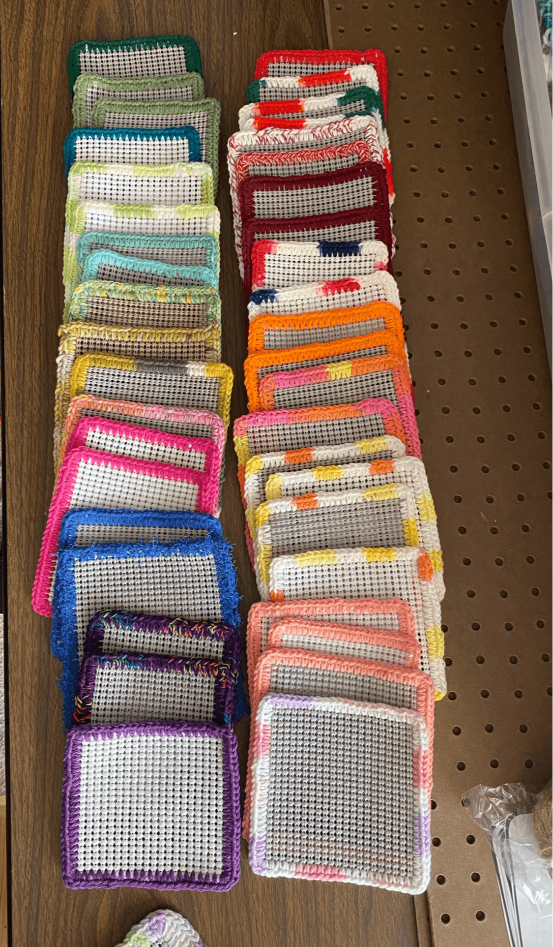 Multiple colorful mesh bags arranged in rows on a brown surface, with various colors including green, red, yellow, pink, blue, and purple.