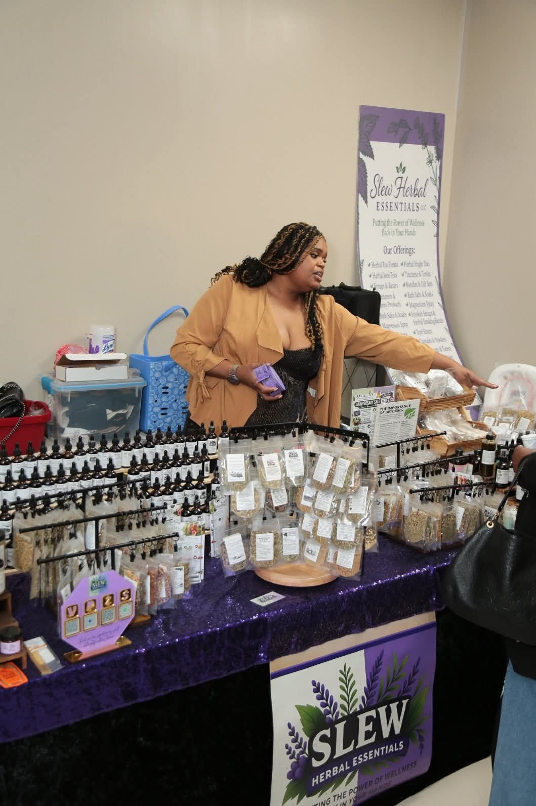 Woman browsing products at a table with essential oils and a SLEW banner in the background.