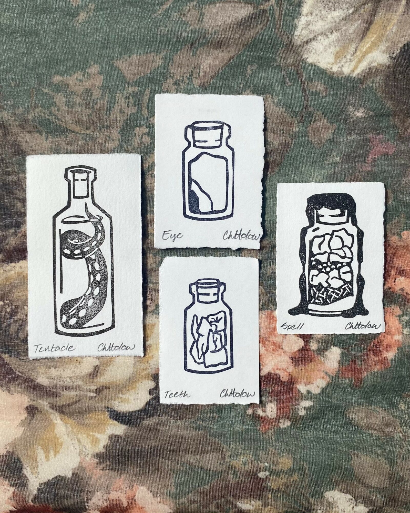 Four small drawings of bottles with different contents on a textured surface, some with handwritten labels.
