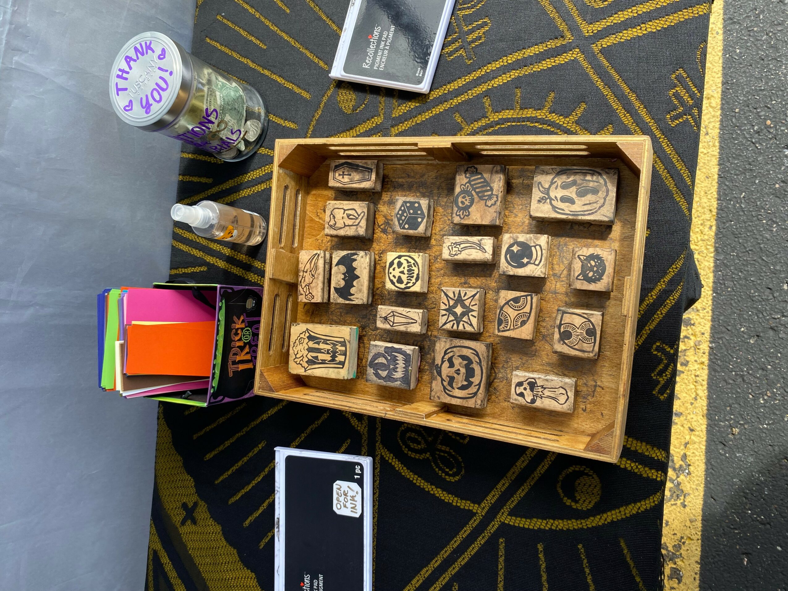 Wooden box with carved stamps, colorful sticky notes, and a thank you sticker on a black and yellow patterned surface.