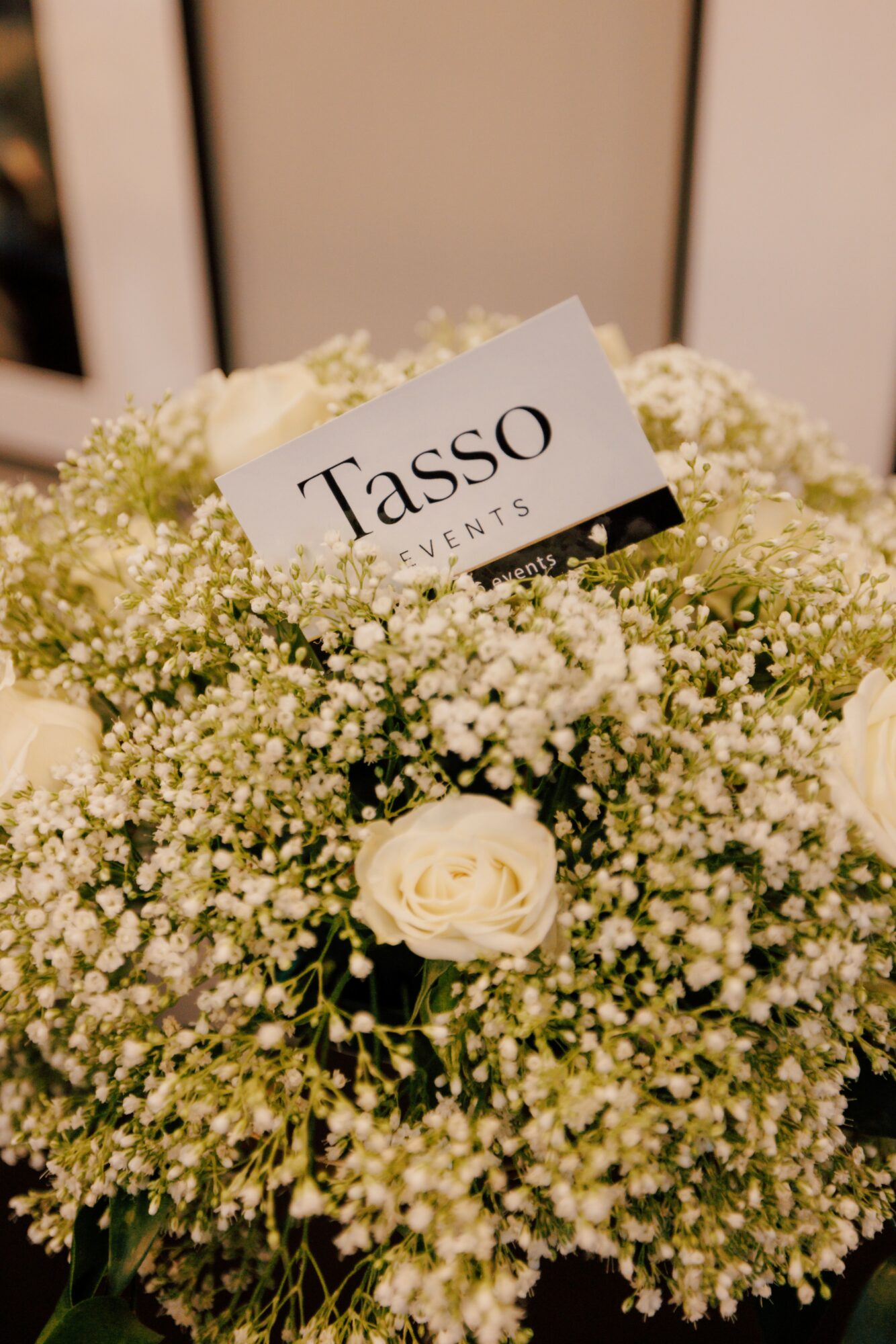 Bouquet of white flowers with a Tasso Events card, against a neutral background.