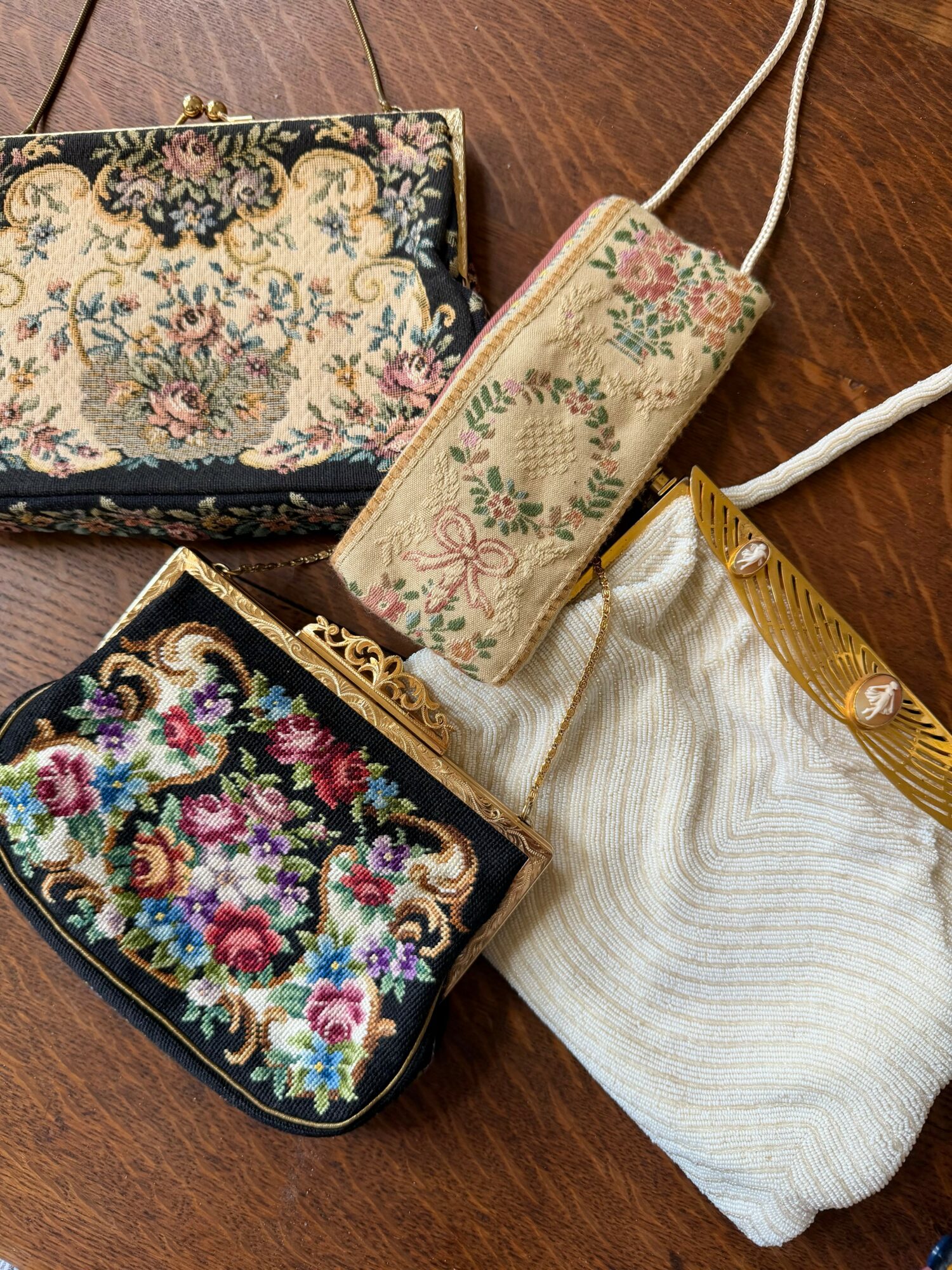 Four embroidered and fabric pouches with floral designs on a wooden surface.