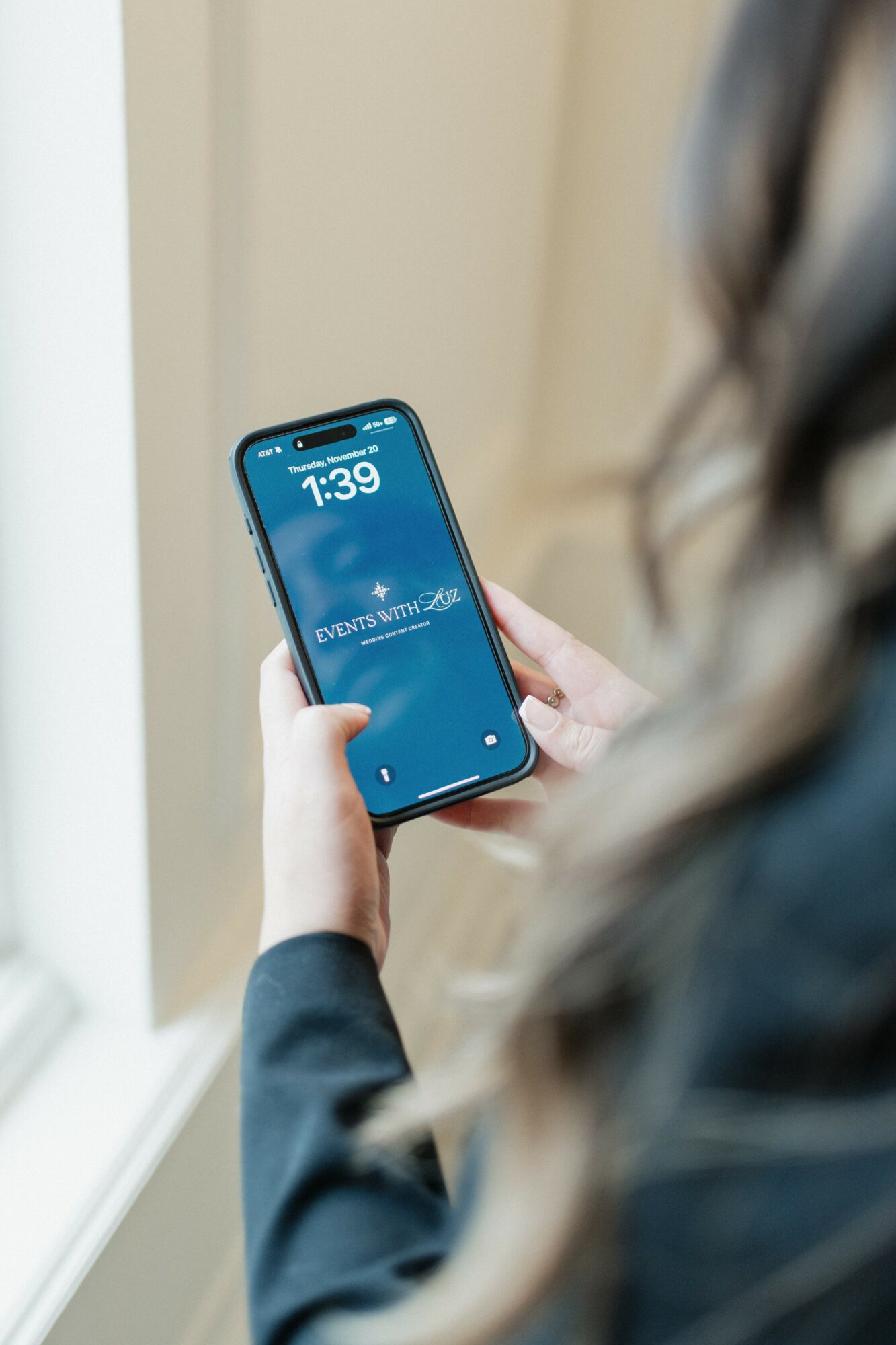 Person holding a smartphone with a blue screen showing the time 1:39 and weather information.