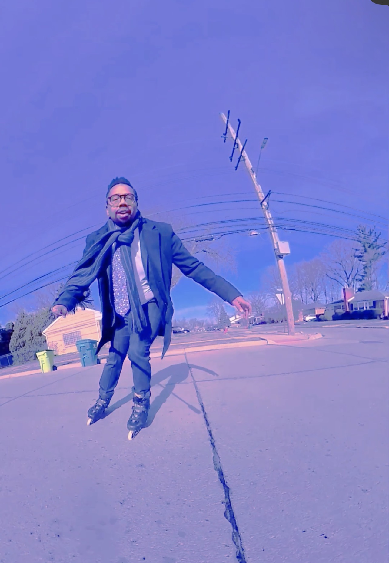 Person standing outdoors on a street, with a tilted utility pole and clear sky in the background.