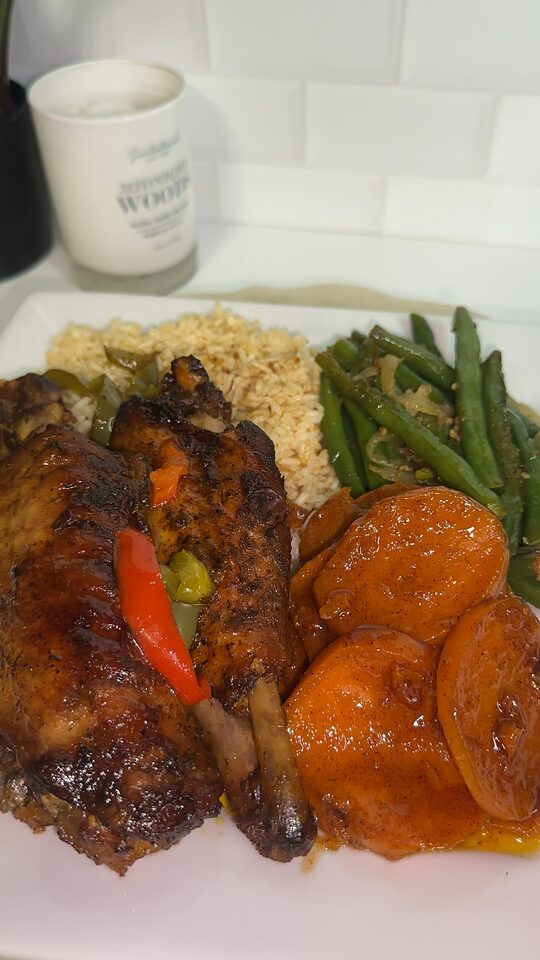 Plate with grilled chicken, green beans, rice, and glazed carrots, with a mug in the background.