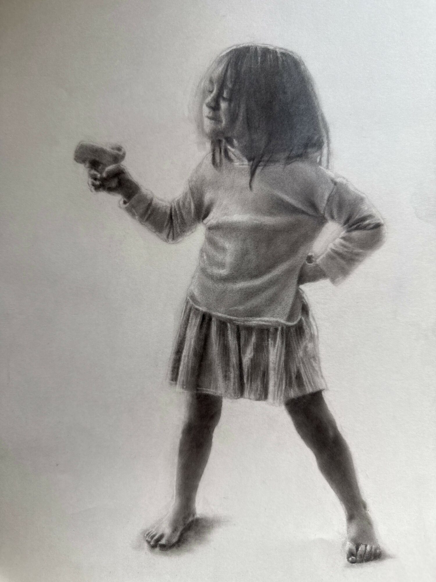 Child standing sideways, holding an object in one hand, wearing a dress and sandals, with hair covering part of the face.