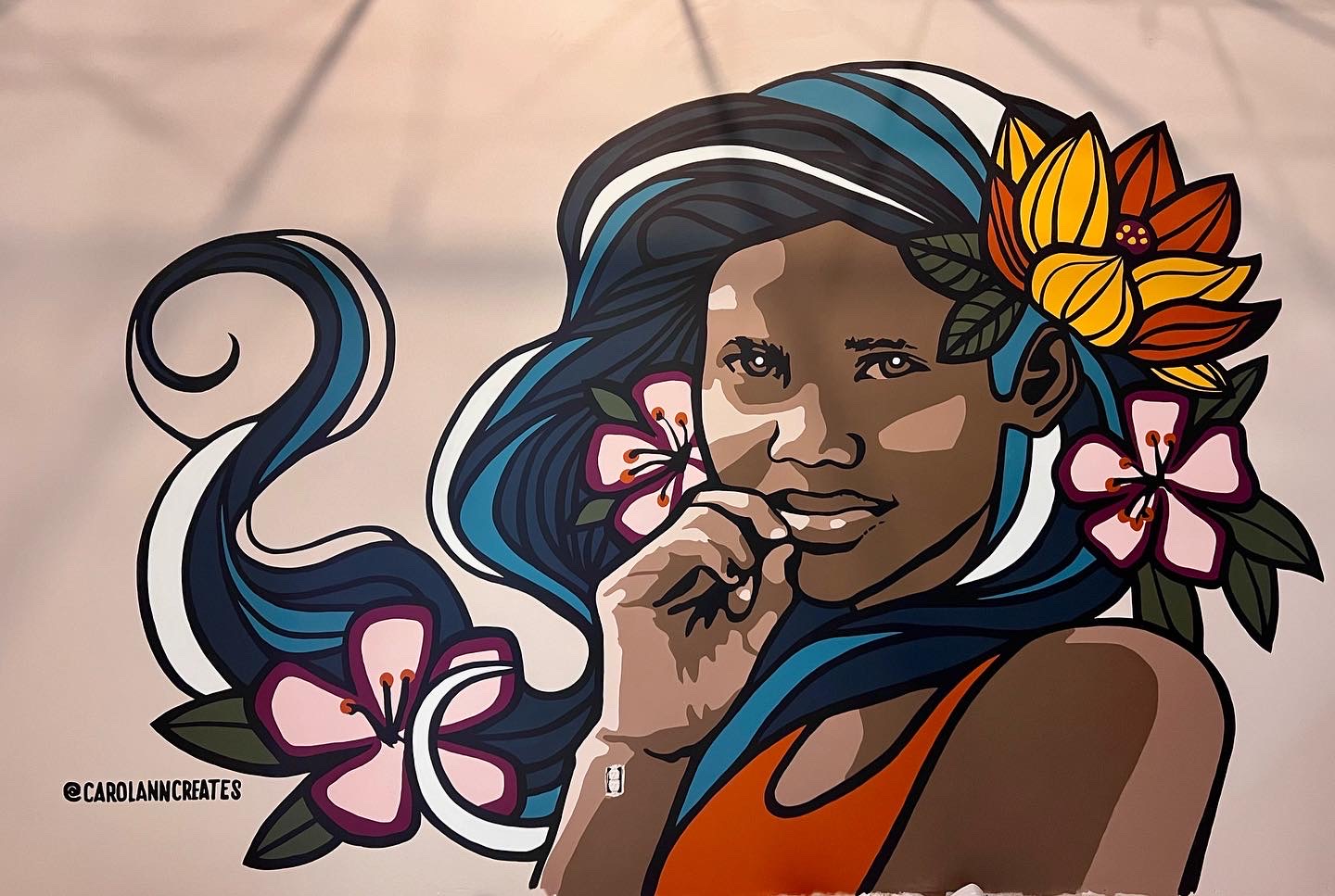 Colorful illustration of a woman with long, flowing hair decorated with flowers and a butterfly, wearing an orange top.