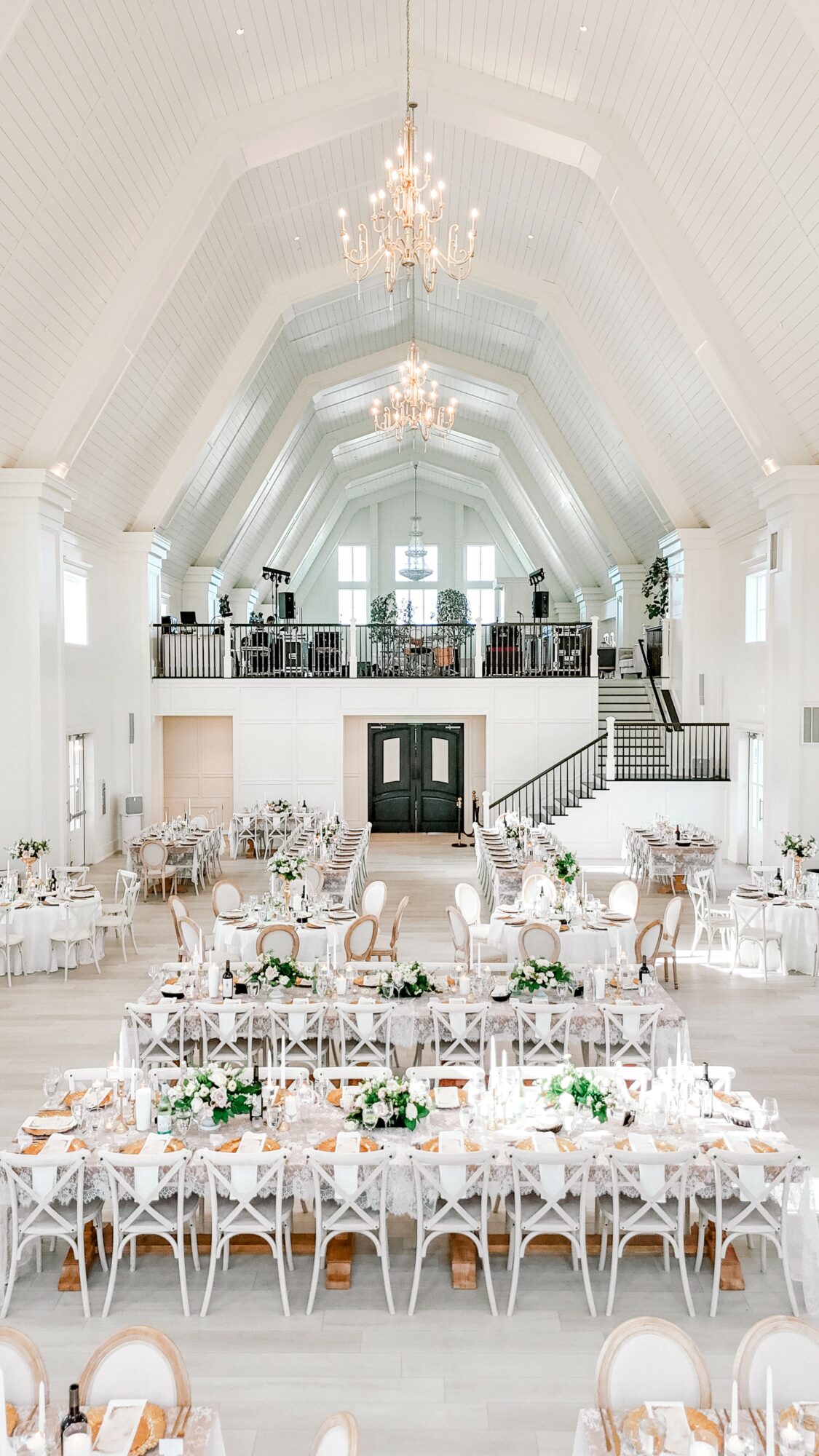 Elegant banquet hall with high vaulted ceiling, chandeliers, and decorated tables for a formal event.