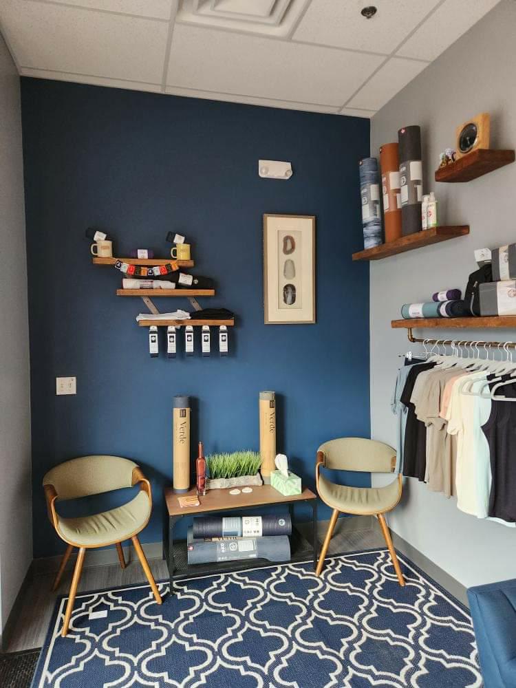 Interior room with two chairs, a small table, wall shelves with decor, and a patterned rug.
