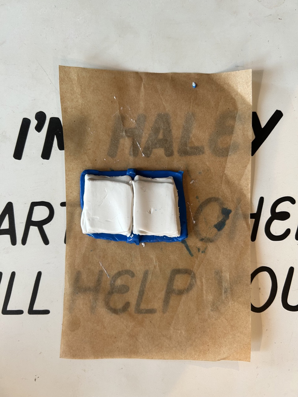Small white object with blue border on brown paper, placed on a white surface with black text.