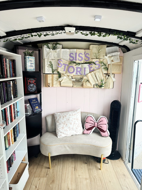 Upside-down view of a cozy corner with a small sofa, butterfly pillow, bookshelf, and a sign reading 'SISS'S STORY'.