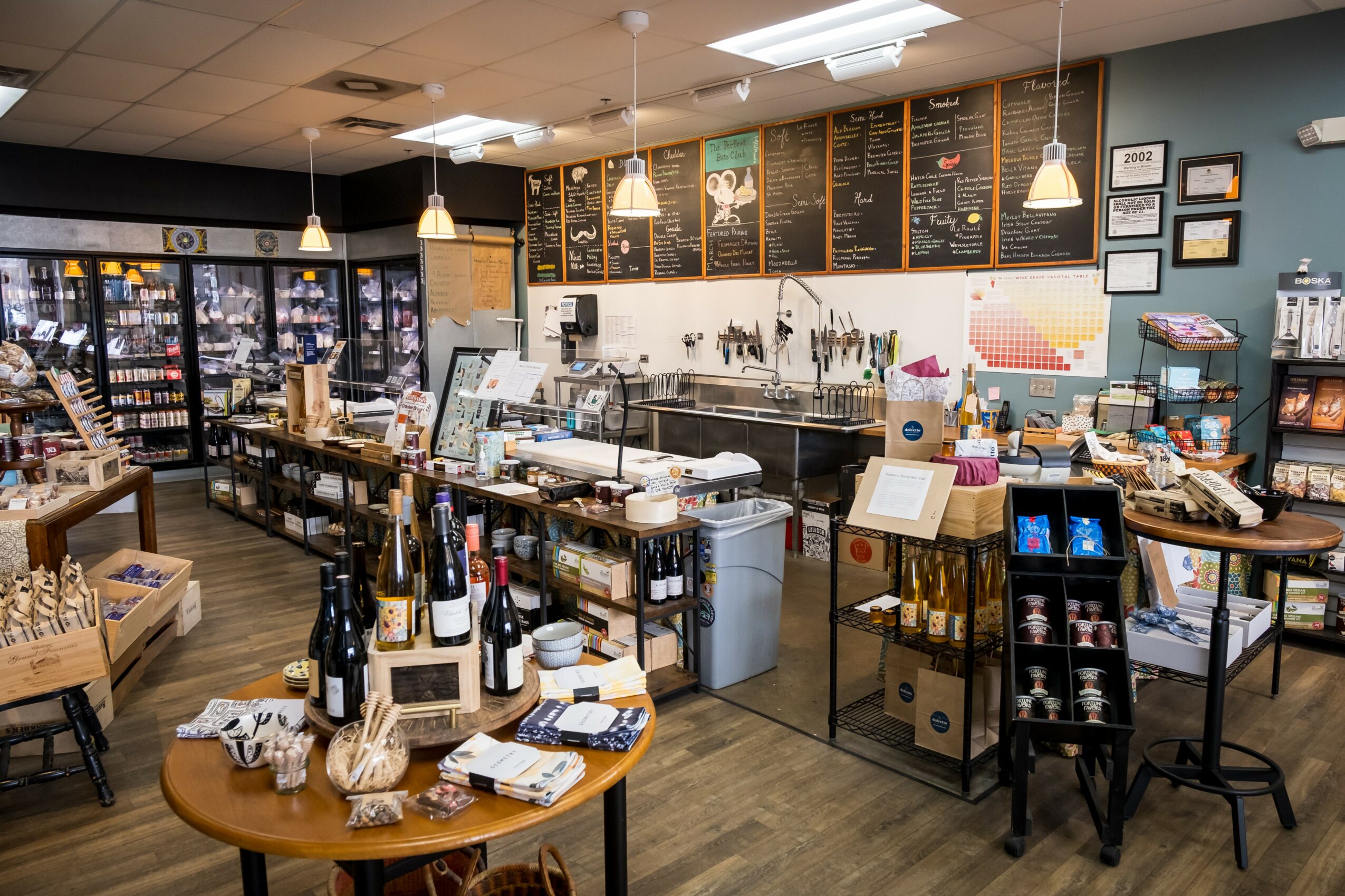Coffee shop interior with menu boards, counter, and seating area, including tables, chairs, and various items on display.
