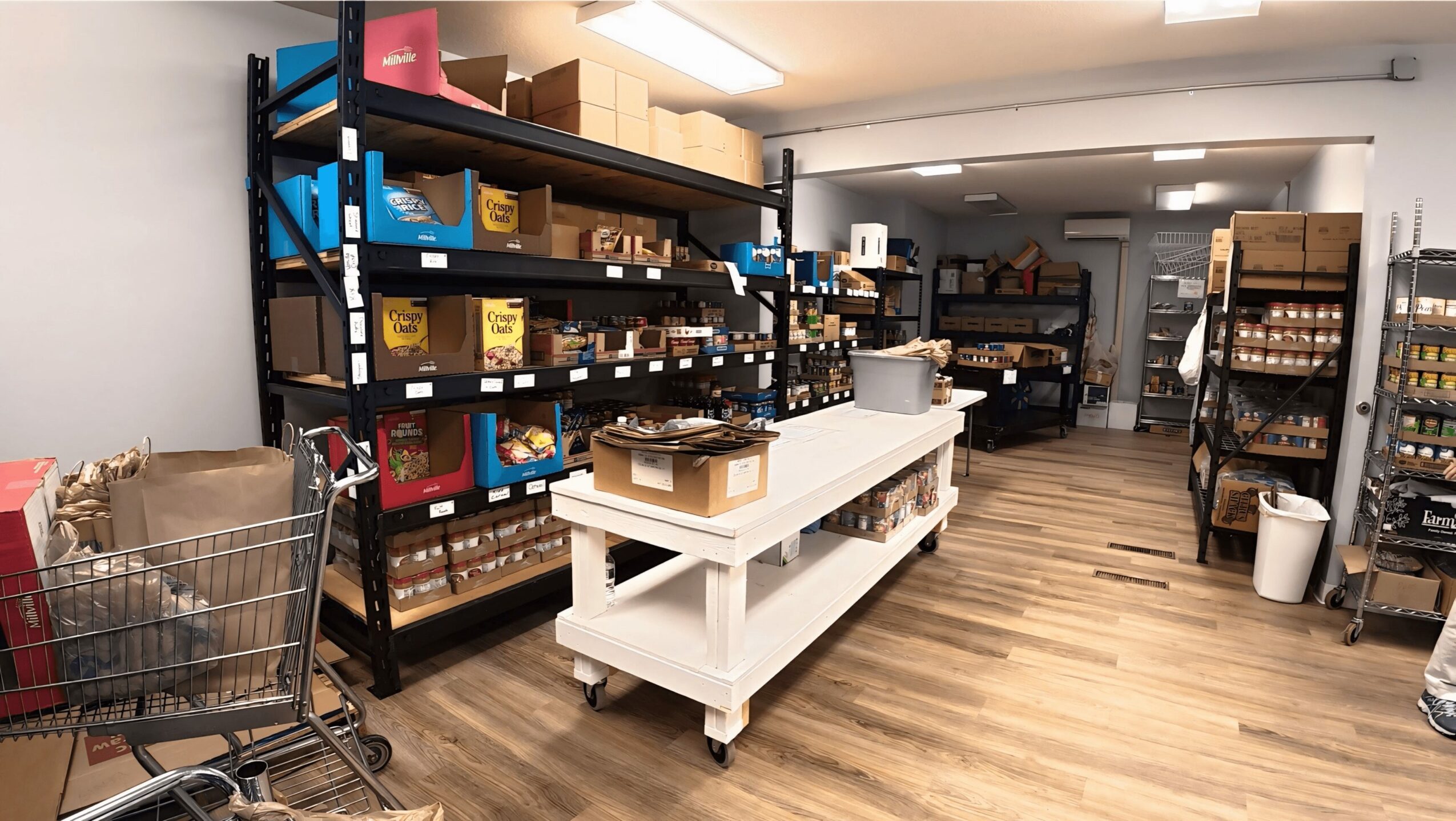 Shelves stocked with boxes and products in a store aisle, with a shopping cart in the foreground.