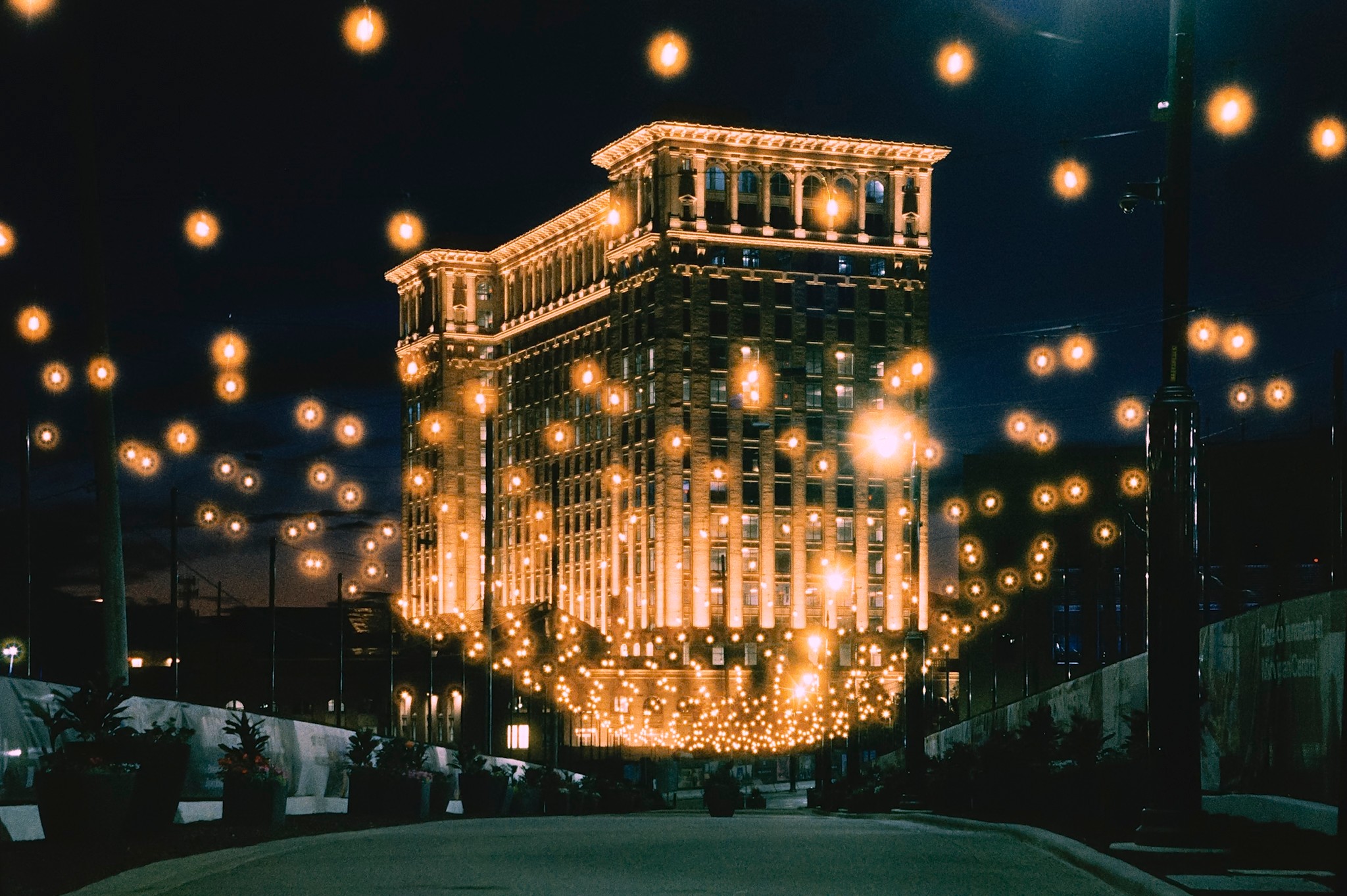 Illuminated building at night with glowing orbs floating around, reflecting in the street below.