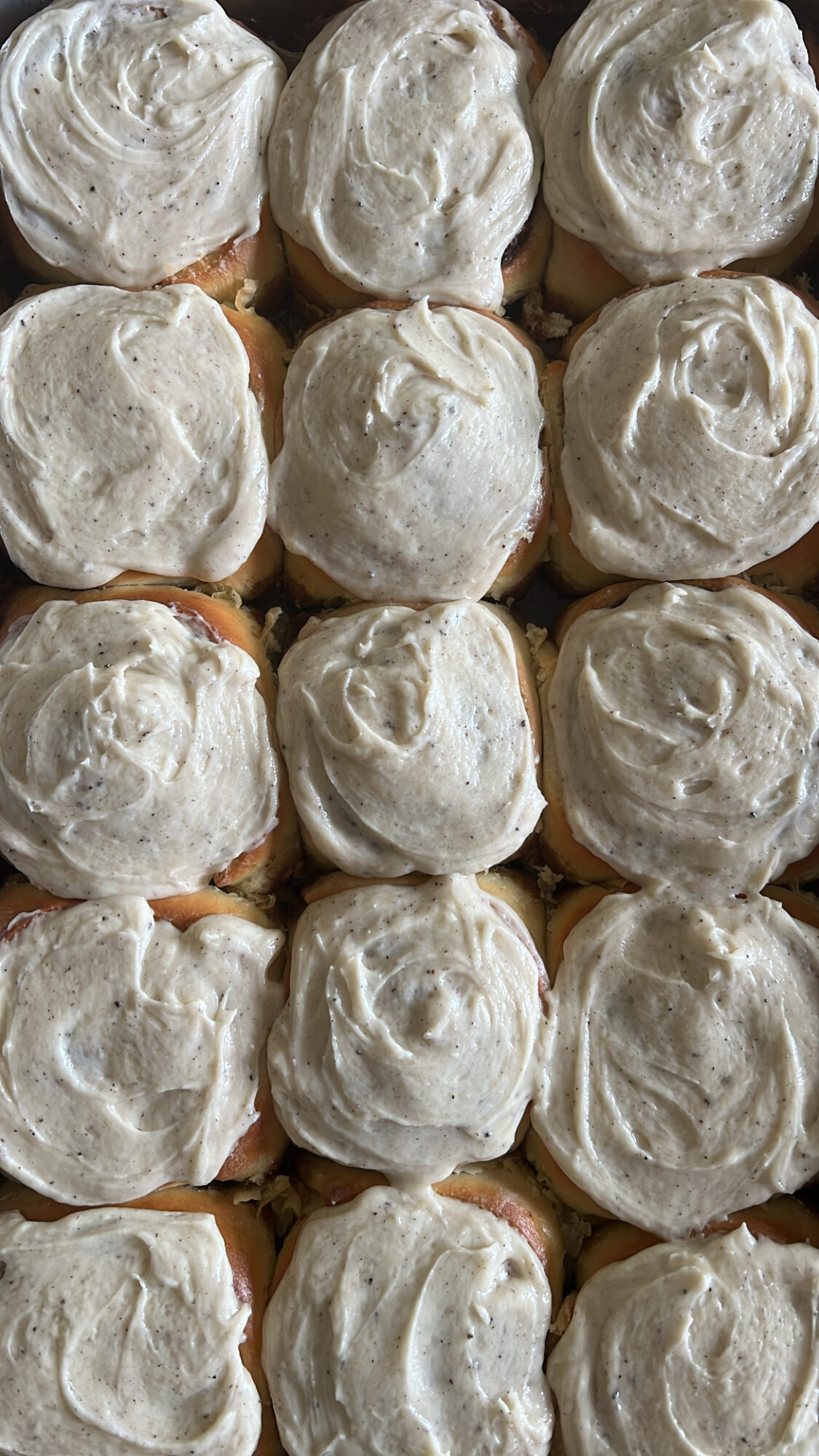 A close-up of multiple cream puffs topped with white icing, arranged in a grid pattern.